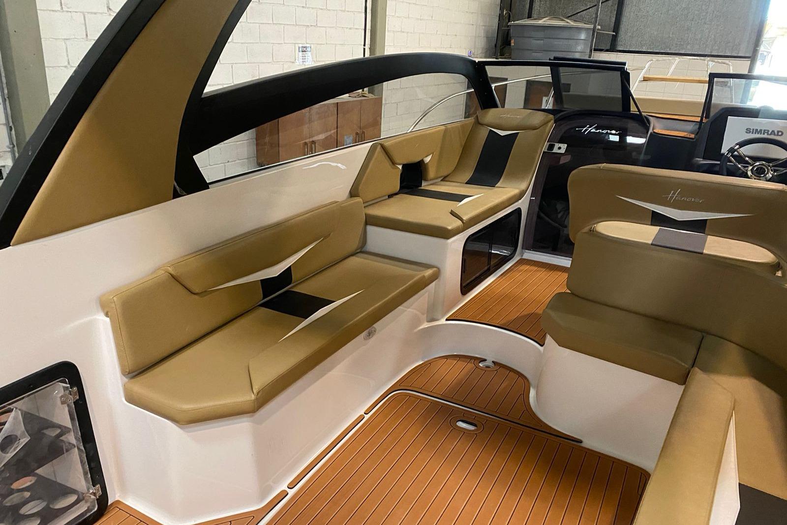 Luxurious interior of 2026 Hanover 305 boat with tan seating and wood flooring.