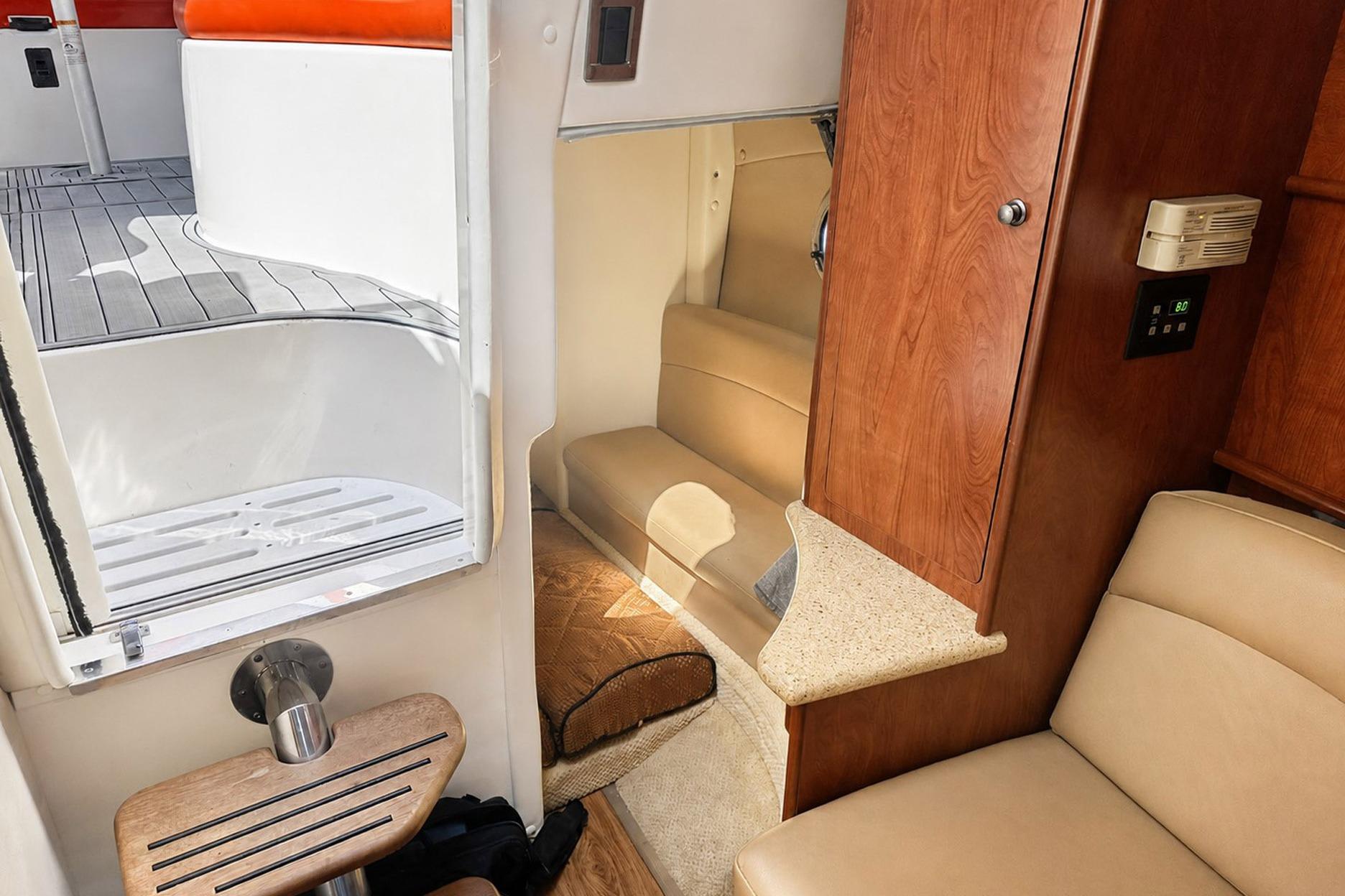 Interior of 2012 Rinker 310 Express Cruiser LE, featuring cozy seating and wooden cabinetry.