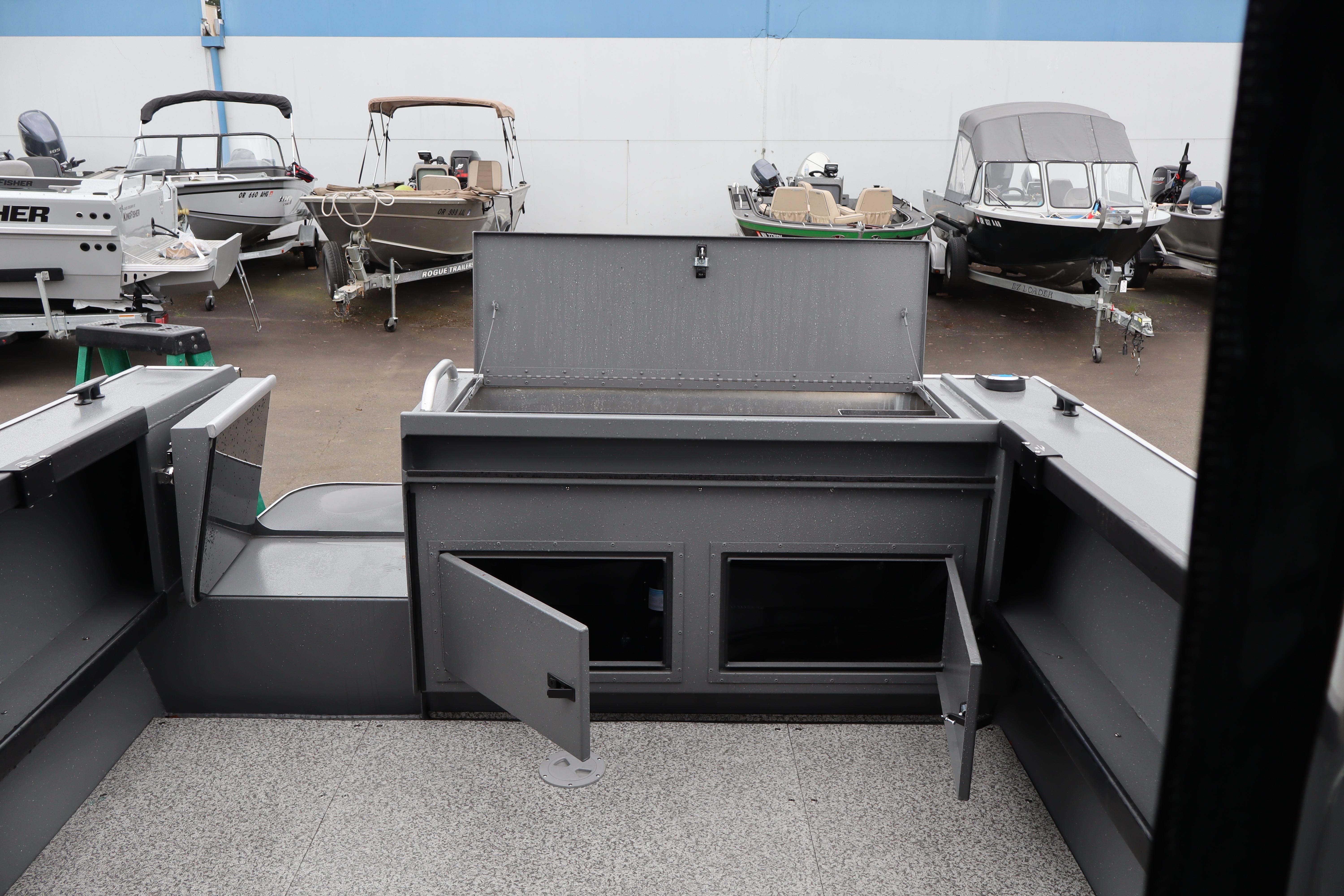 2026 Alumaweld Horizon 24 boat interior with open storage compartments, parked among other boats.