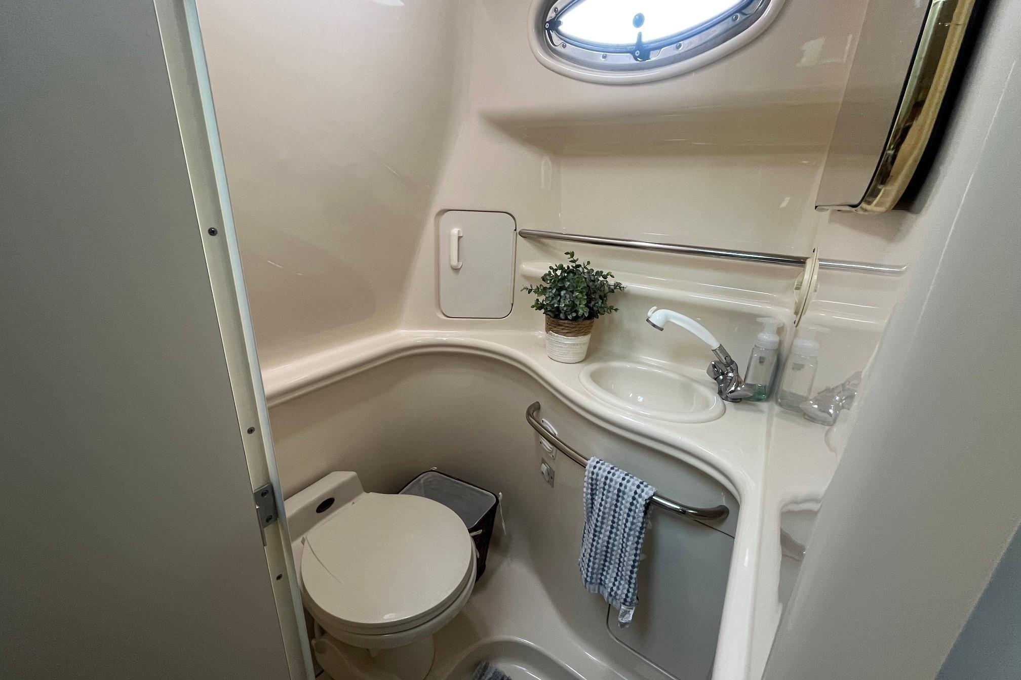 Compact bathroom in 2001 Sea Ray 340 Sundancer yacht with sink, toilet, and porthole window.