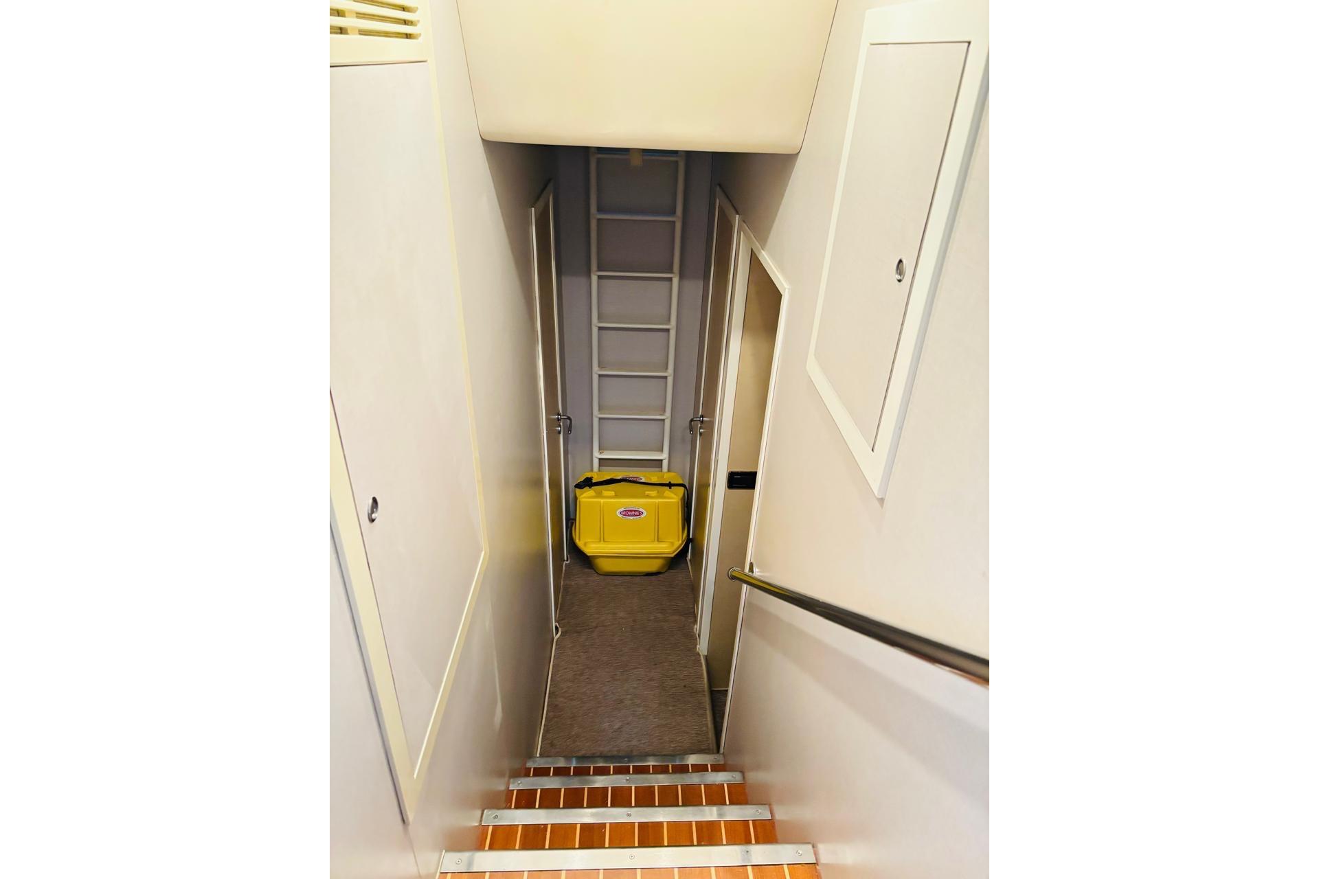 Narrow hallway with stairs and yellow suitcase in a 2000 Falcon 100 aircraft.