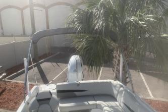 2023 Hurricane SunDeck Sport 188 OB boat near palm tree in parking lot.