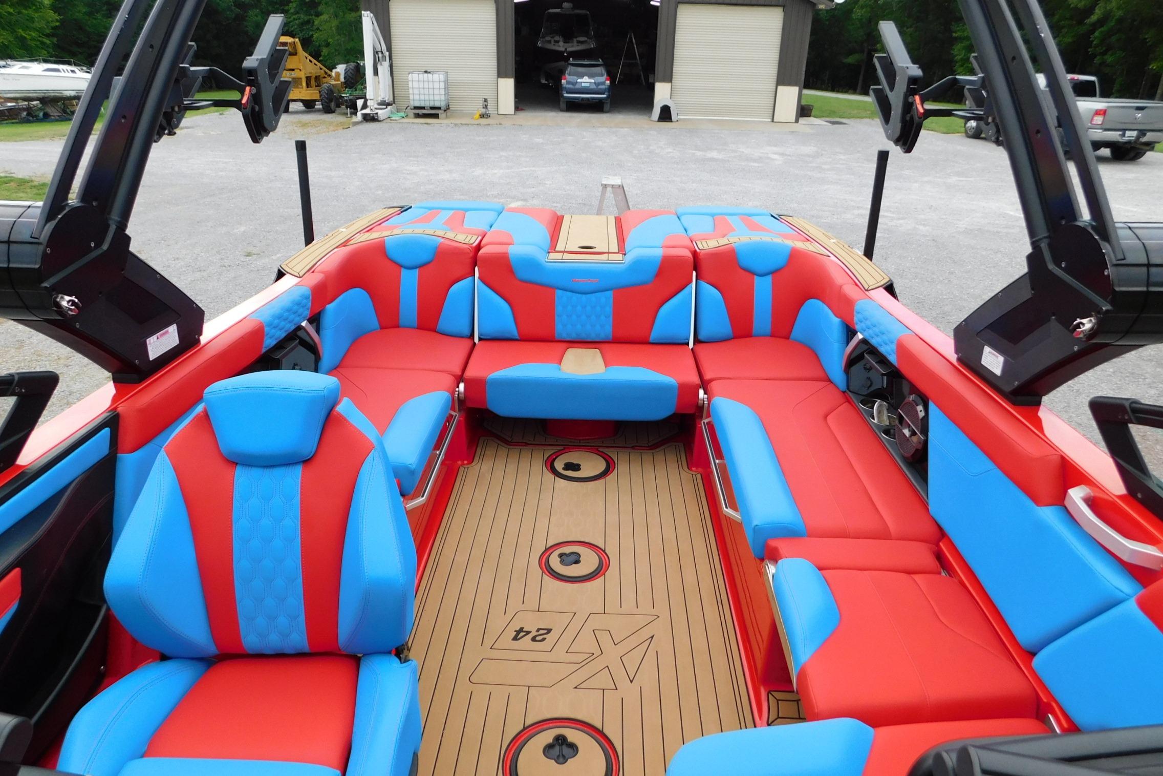 2022 MasterCraft NXT24 boat interior with vibrant red and blue seating, wooden flooring.