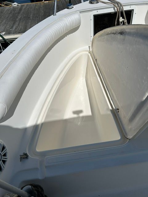 An open storage compartment on a boat with white upholstery and ropes.