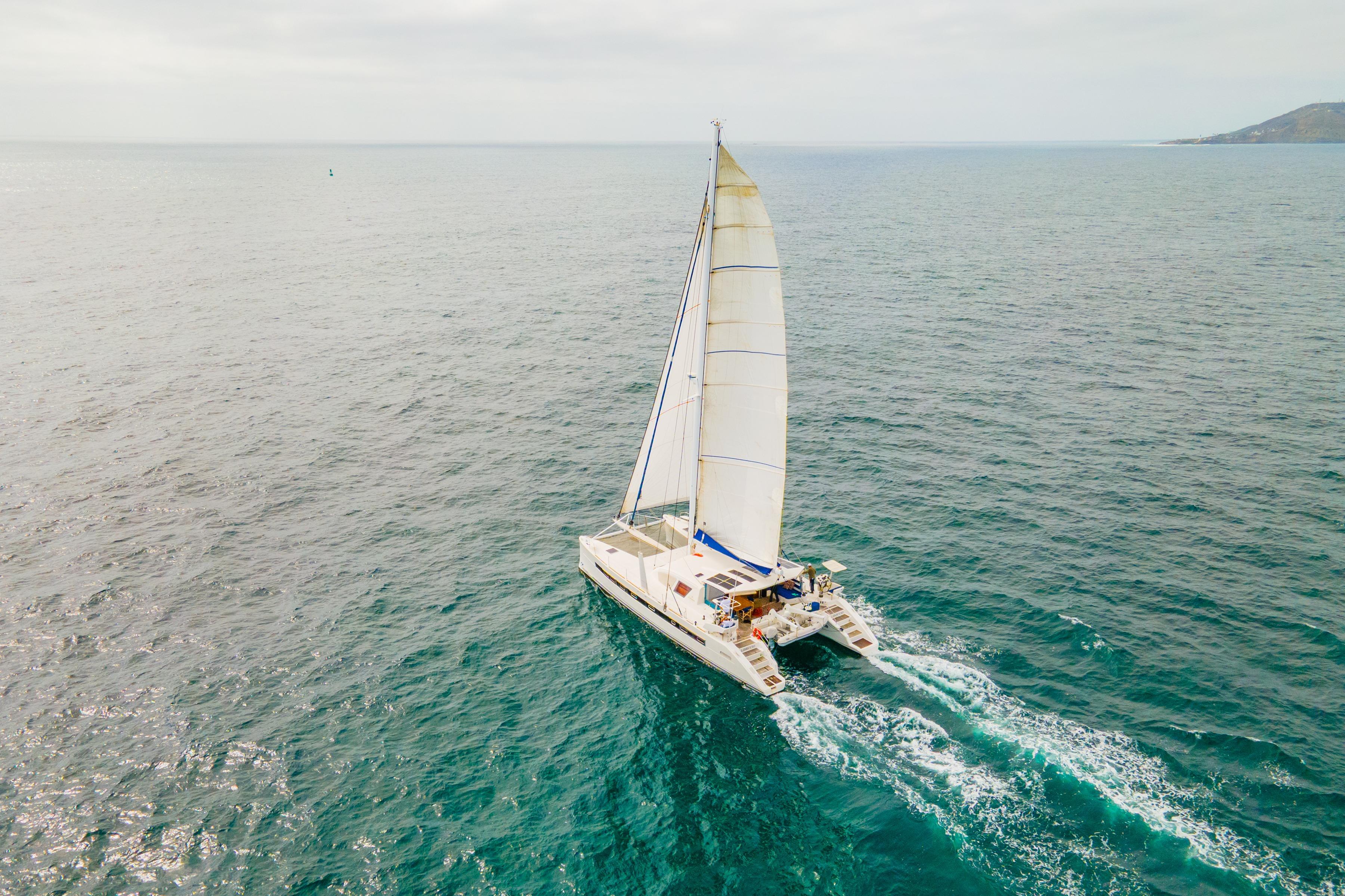 Aerial view of 2009 Catana 65 sailing catamaran cruising on open sea.