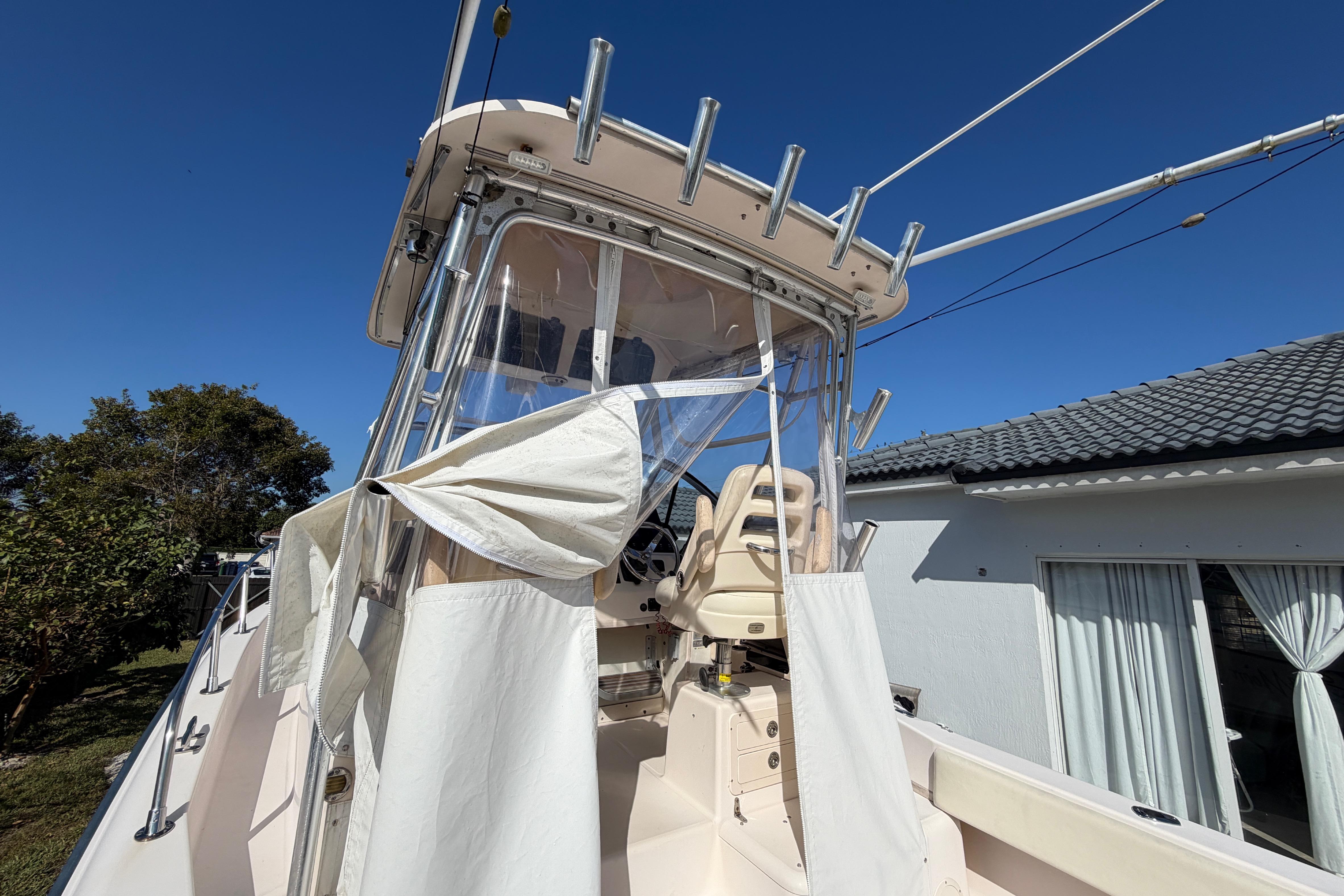 2006 Grady-White Sailfish 282 boat with canopy, docked near a house under clear blue sky.