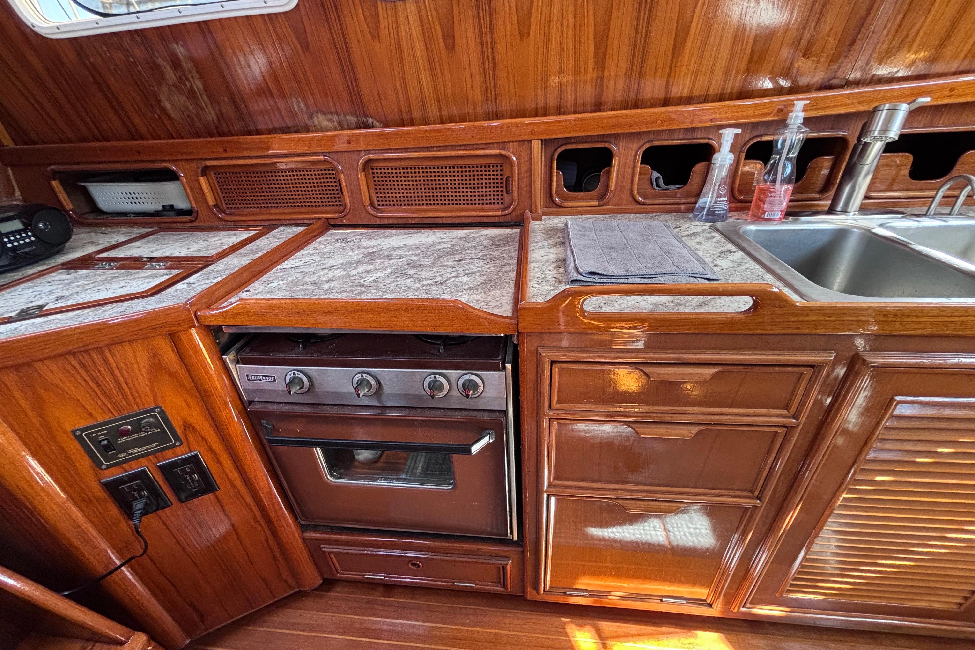 Vintage 1978 Swift 33 yacht kitchen with wooden cabinetry, stove, and sink.