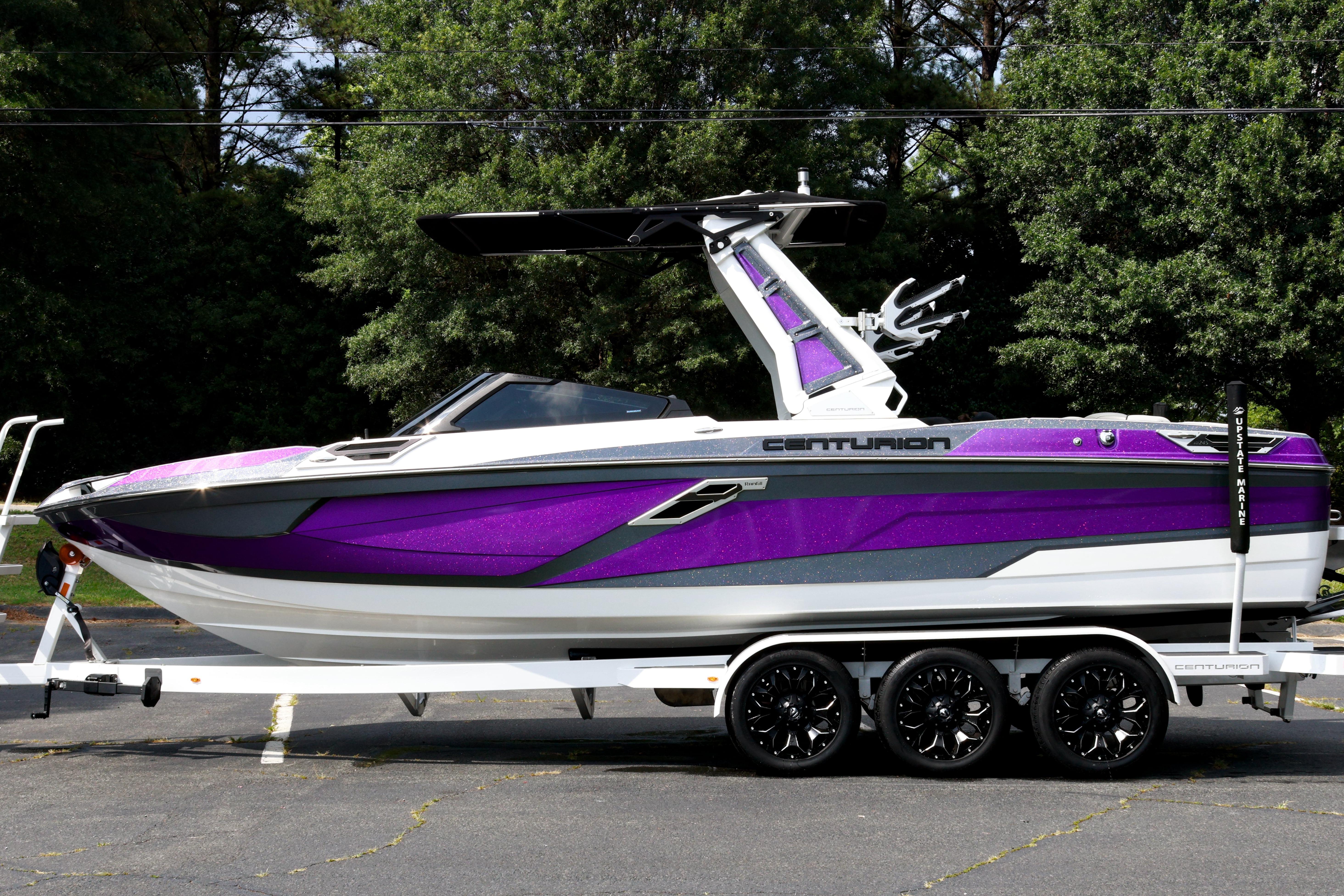 2022 Centurion Ri245 boat in vibrant purple on a trailer, surrounded by trees.