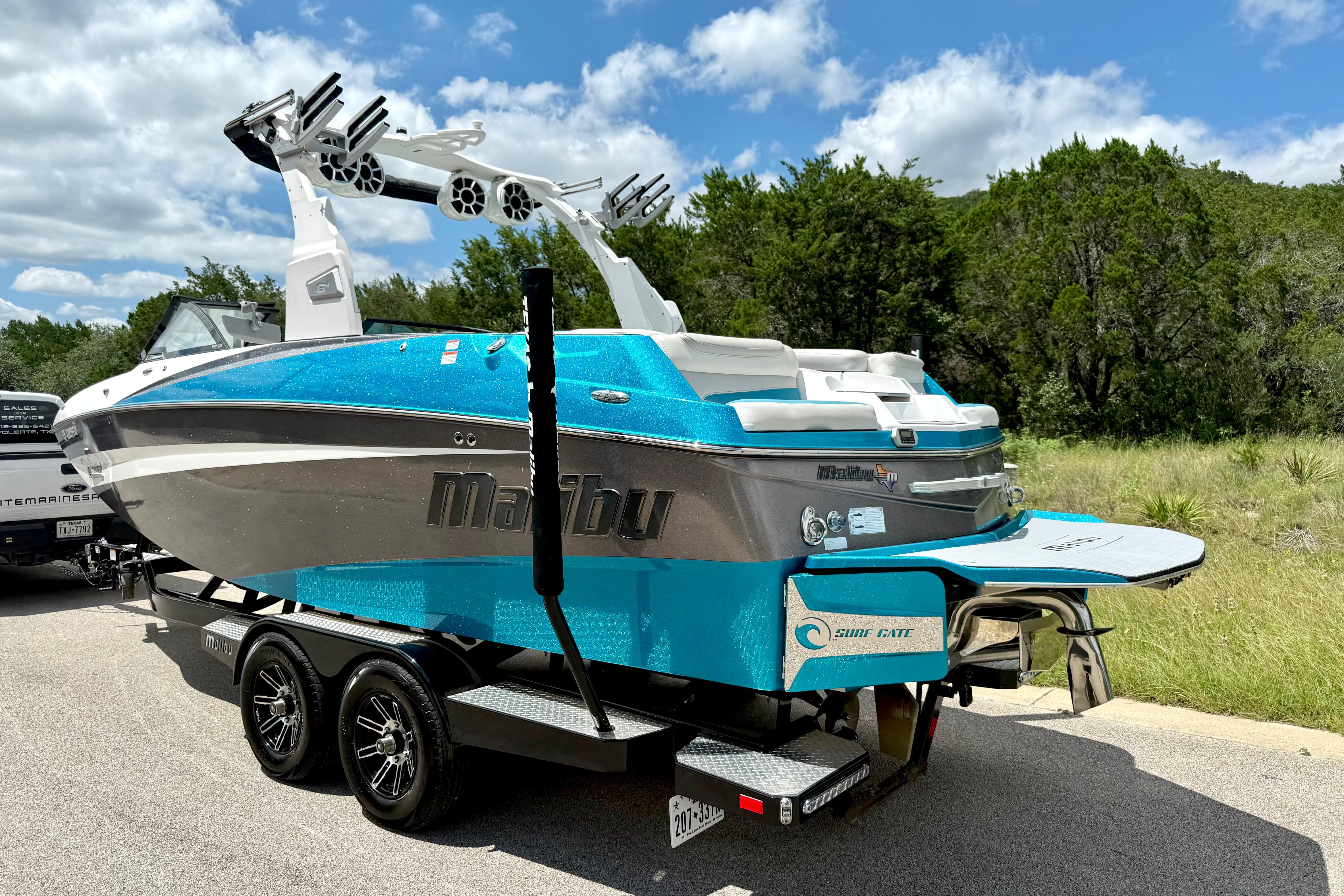 2017 Malibu M235 boat on trailer, vibrant blue and white design, parked outdoors.