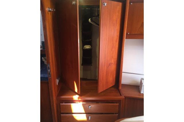 Wooden wardrobe with open doors and drawers in a 1997 Gorbon Custom 66 yacht.