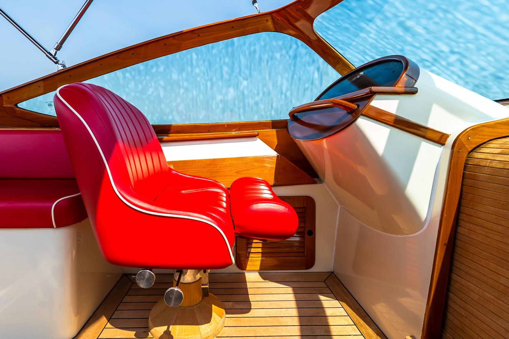 Red leather seat in 2005 Hinckley Talaria 29R boat cockpit with wooden accents.