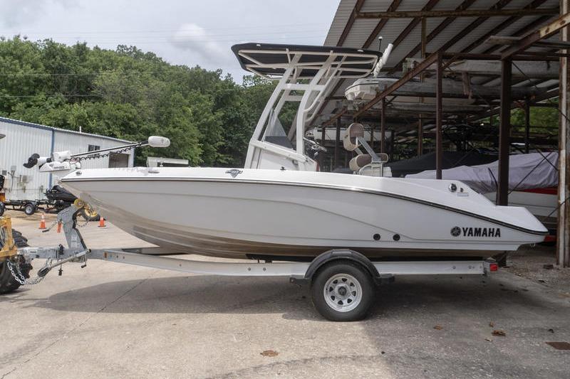 2023 Yamaha Boats 195 FSH Sport on trailer, parked outdoors near a storage facility.