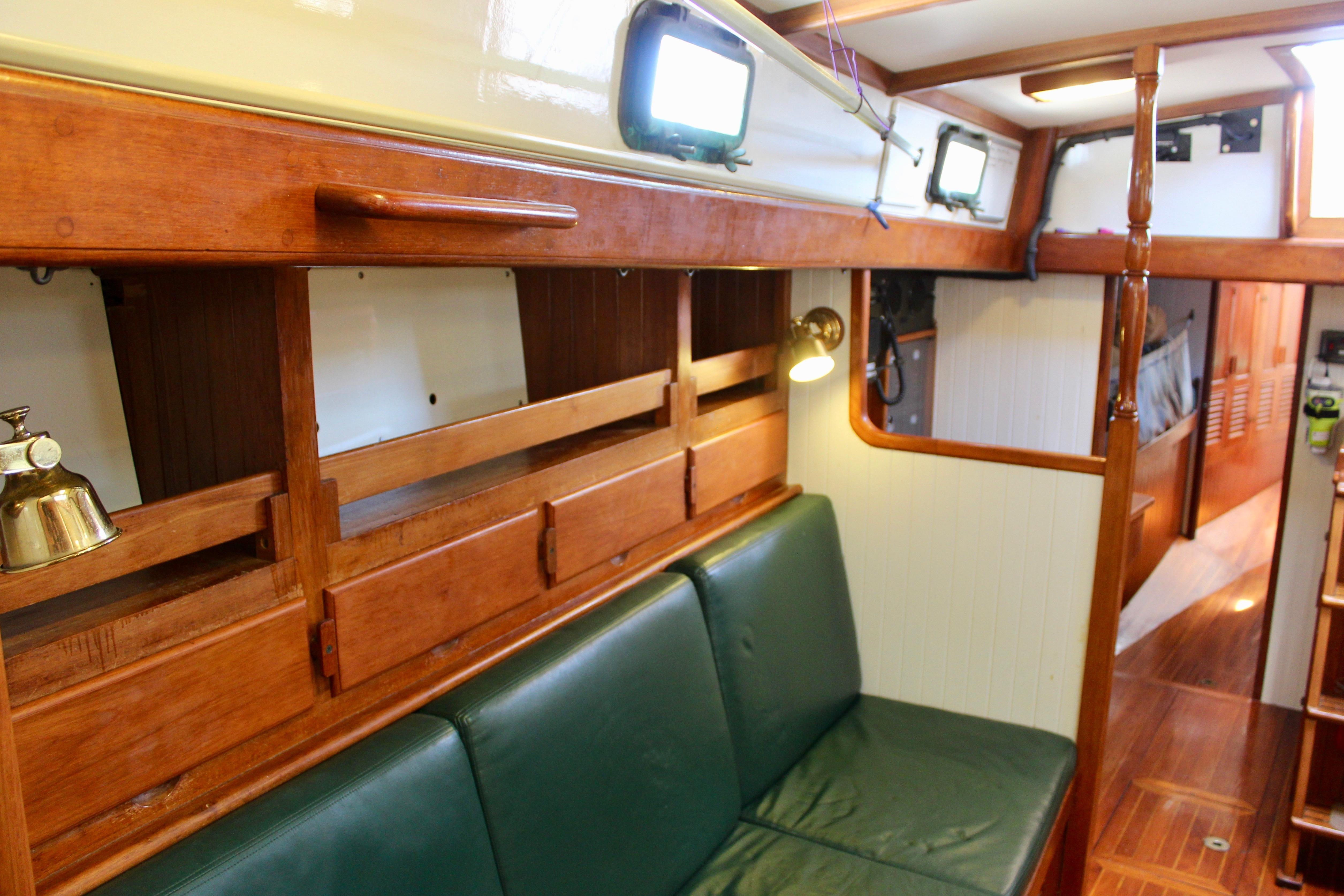 Interior of a 1981 Kelly Peterson 46 sailboat with wooden cabinetry and green seating.