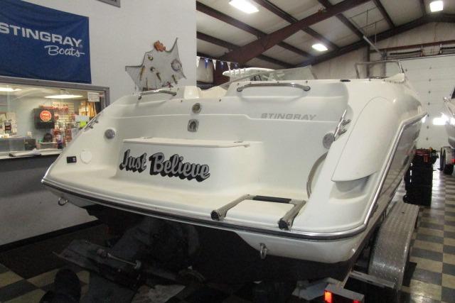 2004 Stingray 240 LR boat in showroom, rear view with "Just Believe" text.