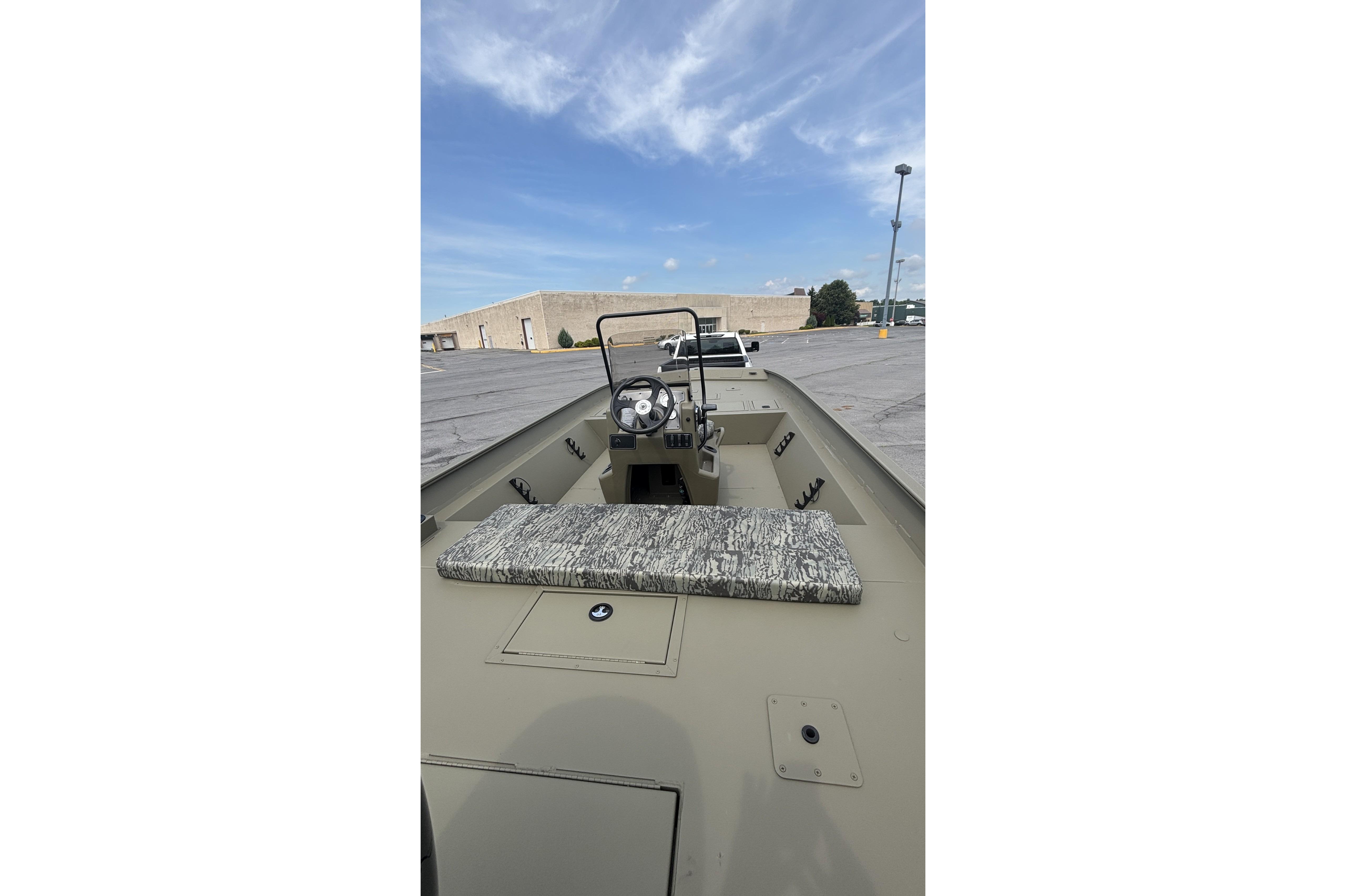 2026 Tracker Grizzly 2072 CC boat interior with steering console, parked outdoors under blue sky.