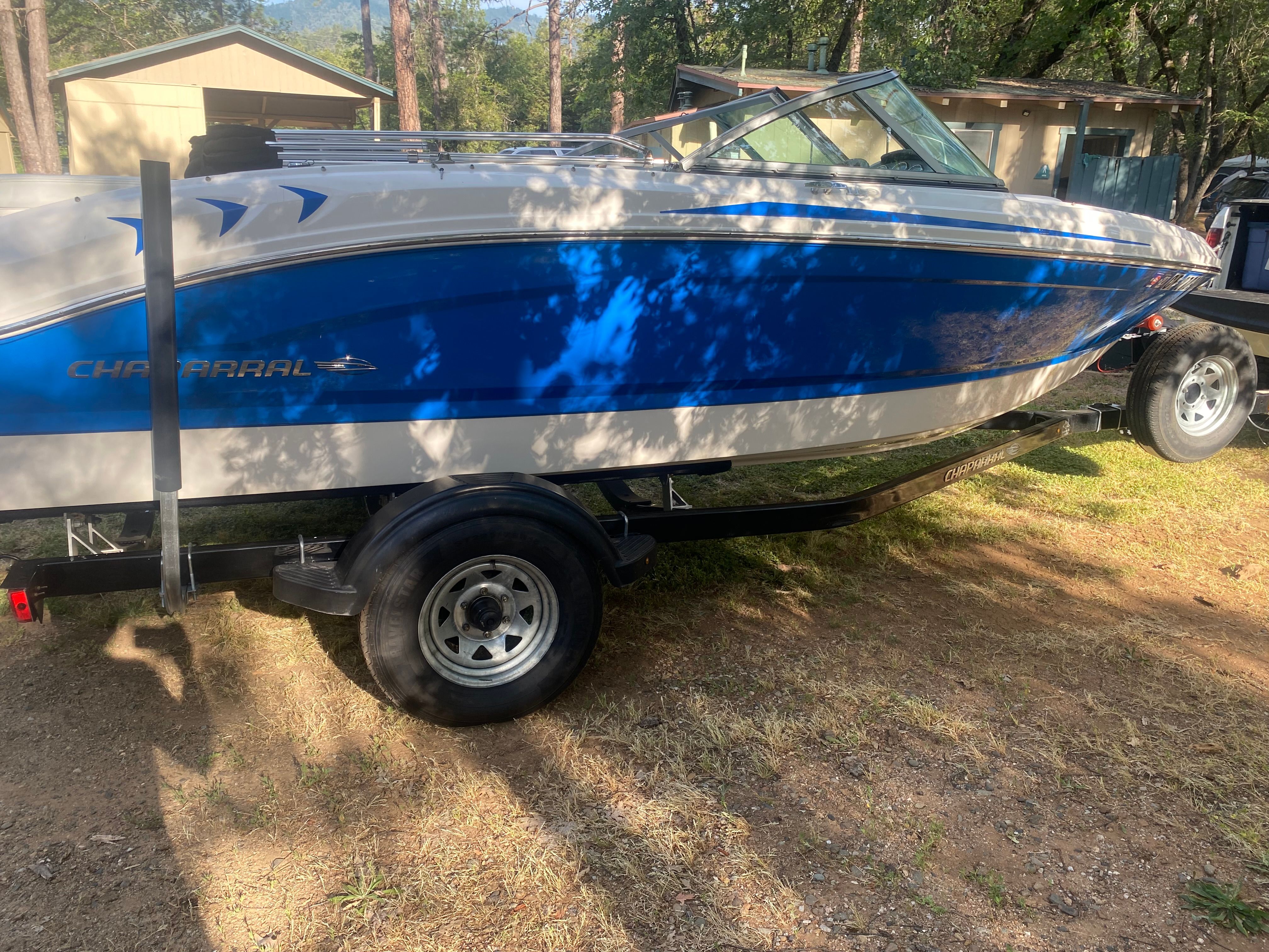 A blue and white 2017 Chaparral 19 H2O Sport on a trailer outdoors.