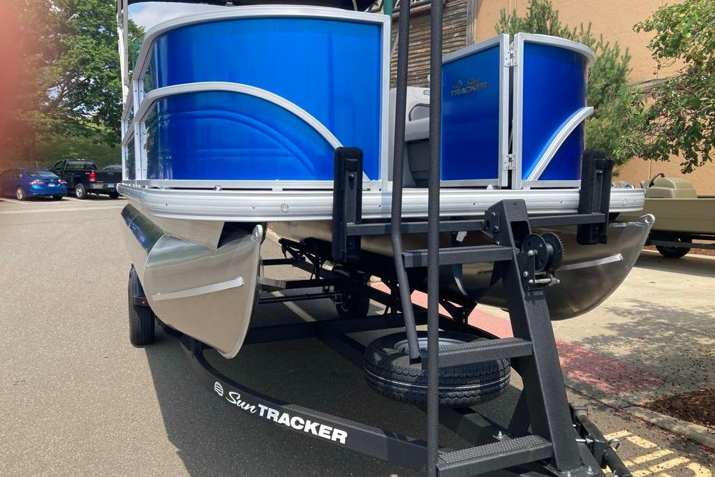 2026 Sun Tracker Party Barge 18 DLX pontoon boat on trailer, vibrant blue exterior.
