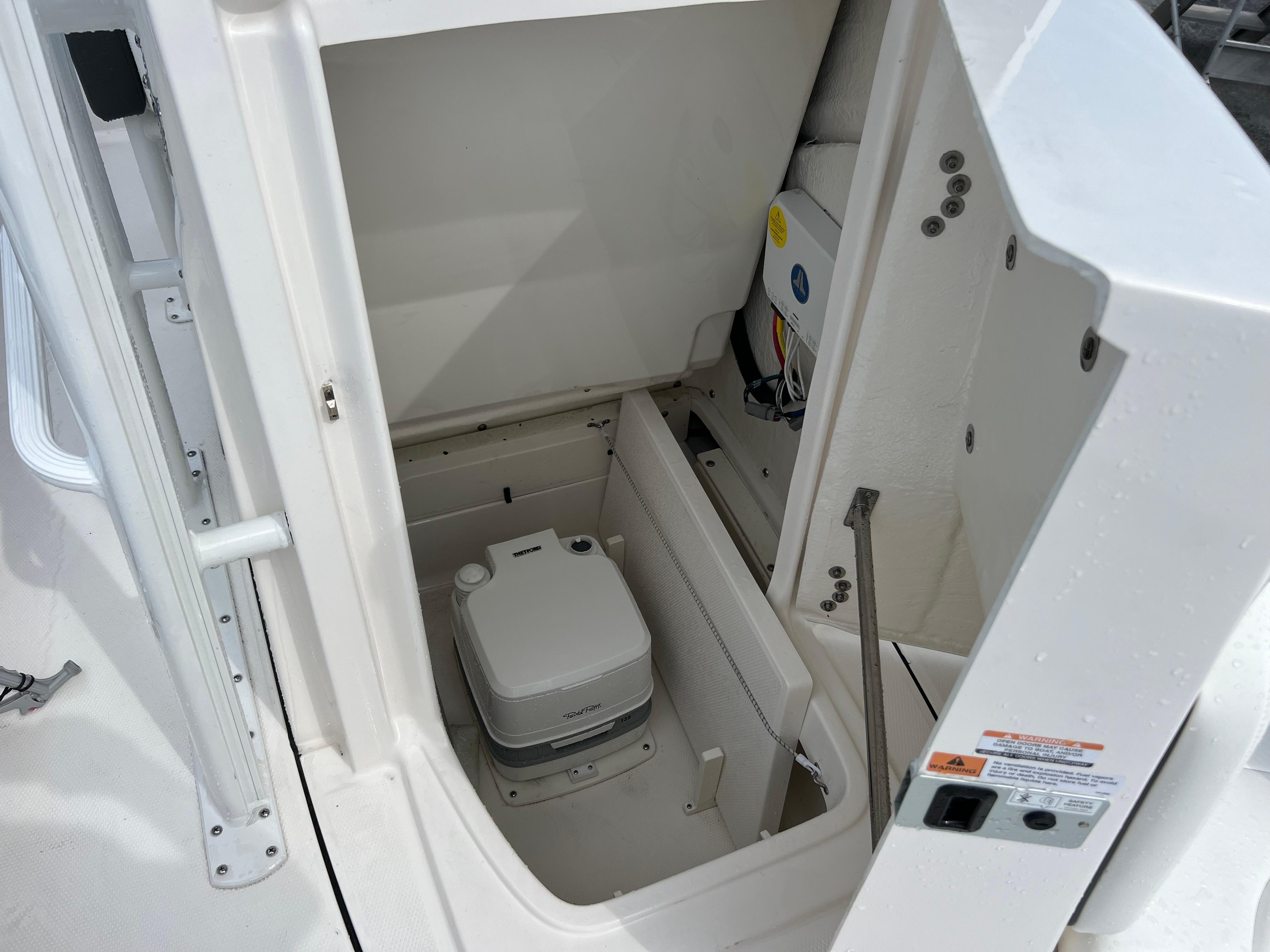 2024 Robalo 246 Sky Deck boat interior storage compartment with portable toilet.