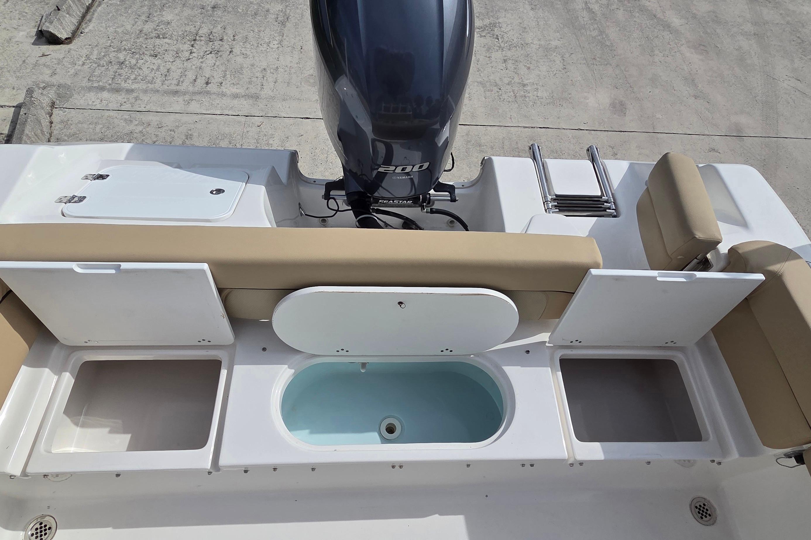 2015 Tidewater 220 LXF boat with open storage compartments and outboard motor.