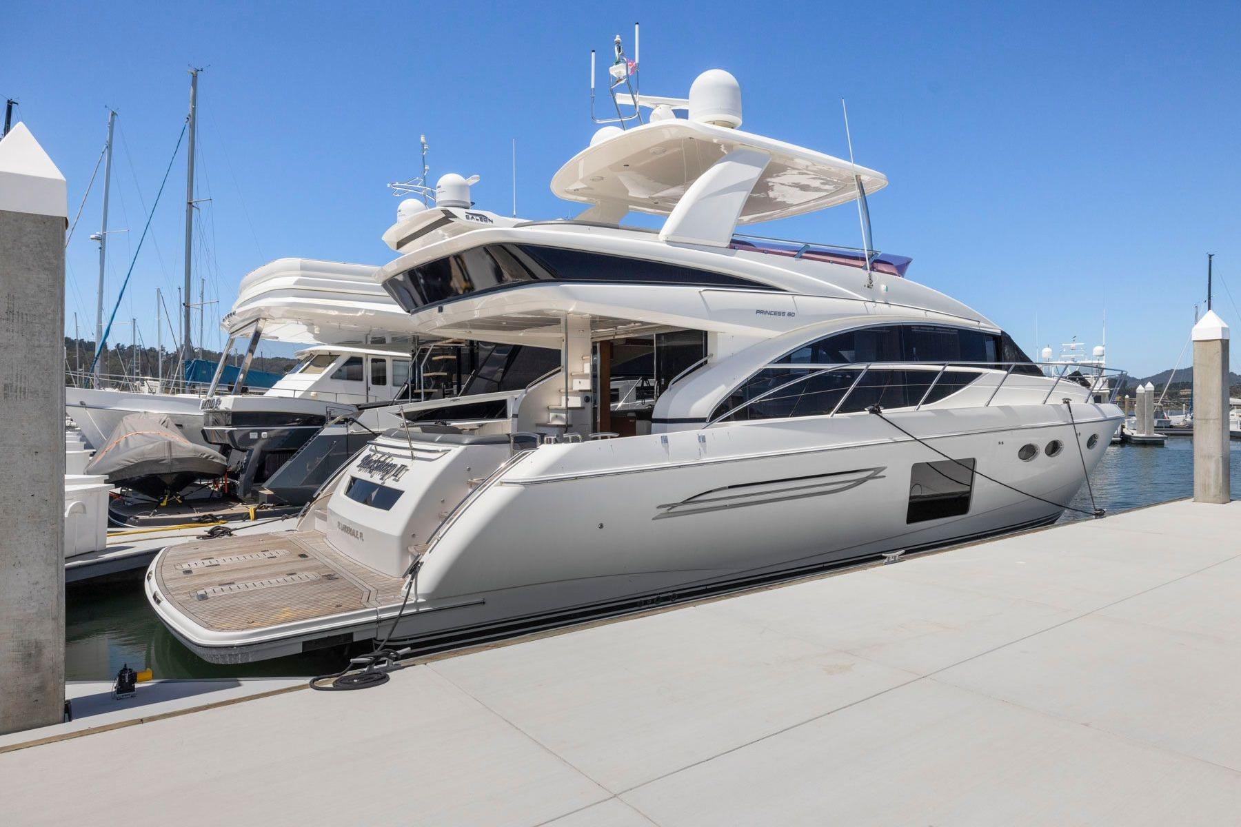 2015 Princess 60 Flybridge Motor Yacht docked at marina under clear blue sky.