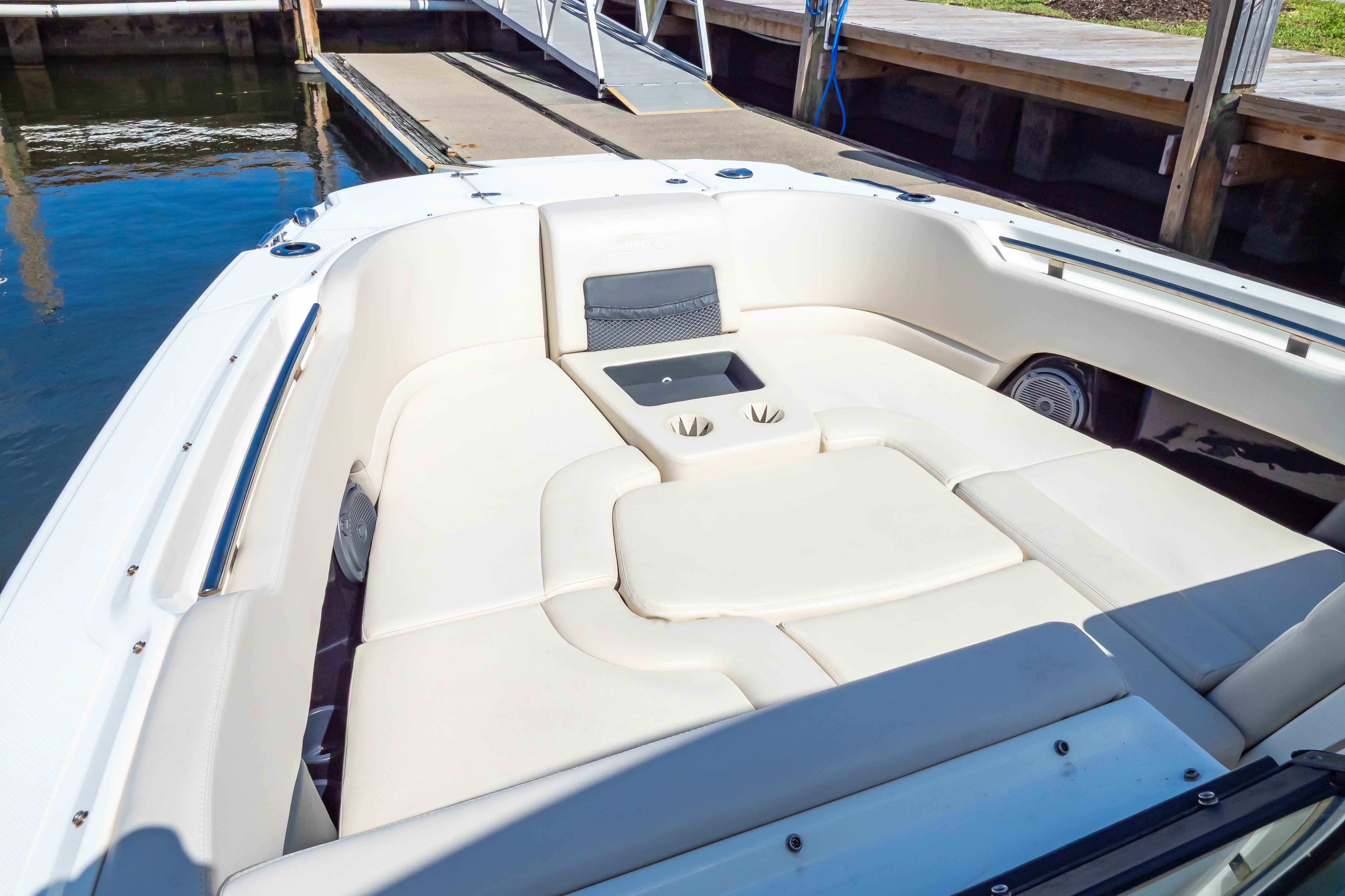 2019 Boston Whaler 270 Vantage boat interior with cushioned seating and cup holders at dock.
