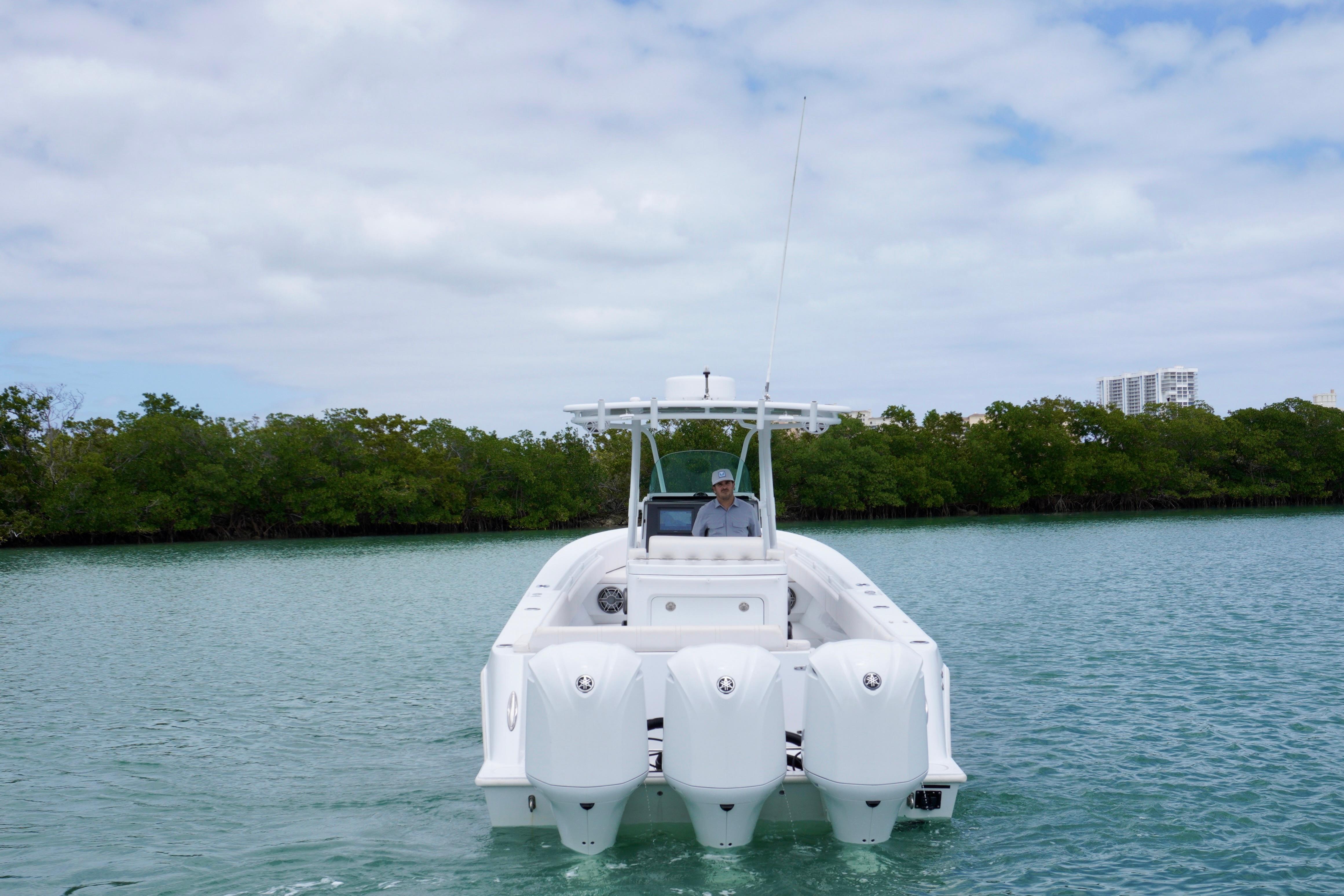 2013 Contender 35 LS boat with triple engines on calm water, surrounded by greenery.