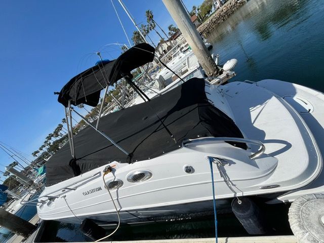 A white Glastron boat with a black canopy is docked on the water.