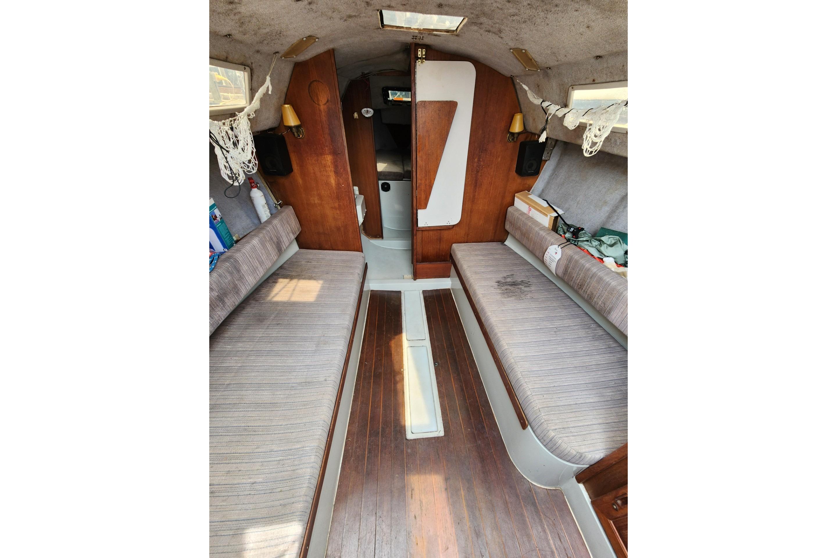 Interior of a 1988 O'Day 272 LE sailboat with wooden flooring and cushioned seating.