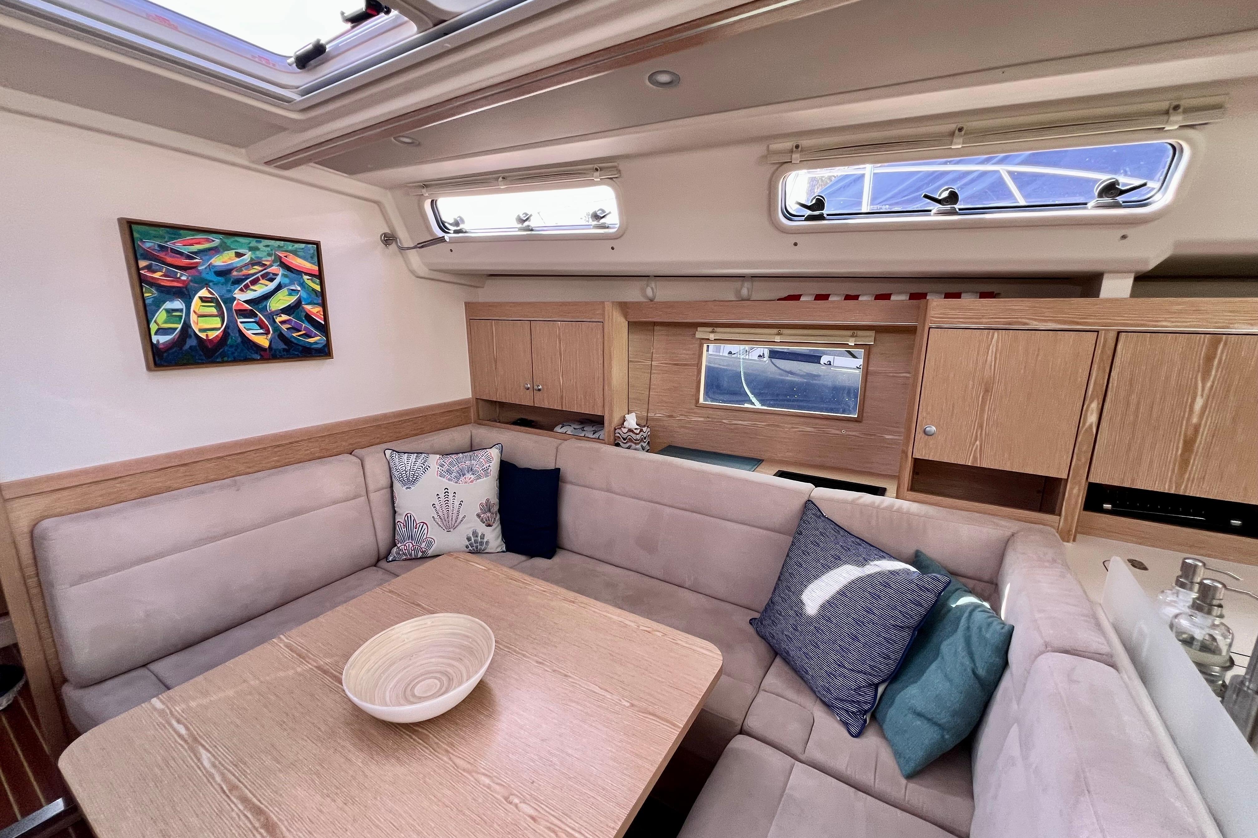 Interior of 2016 Hanse 455 yacht with cozy seating, cushions, and colorful boat painting.
