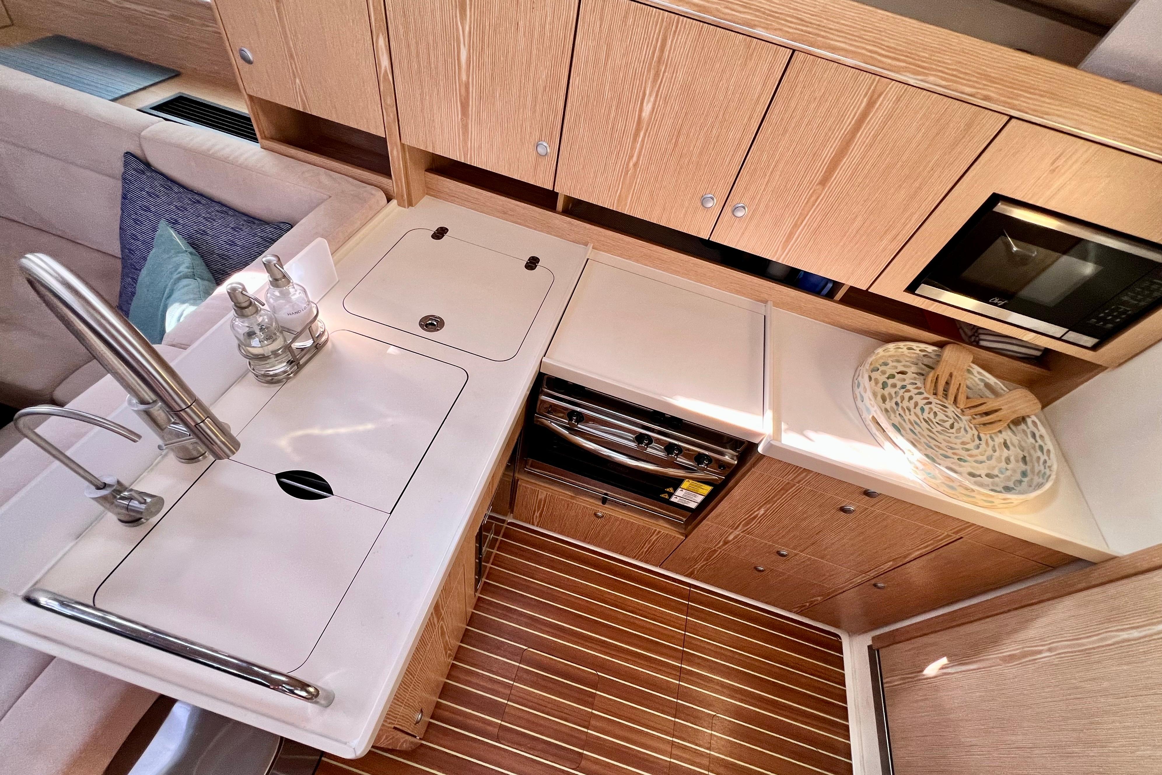 Modern kitchen interior of 2016 Hanse 455 yacht with wooden cabinetry and sleek appliances.