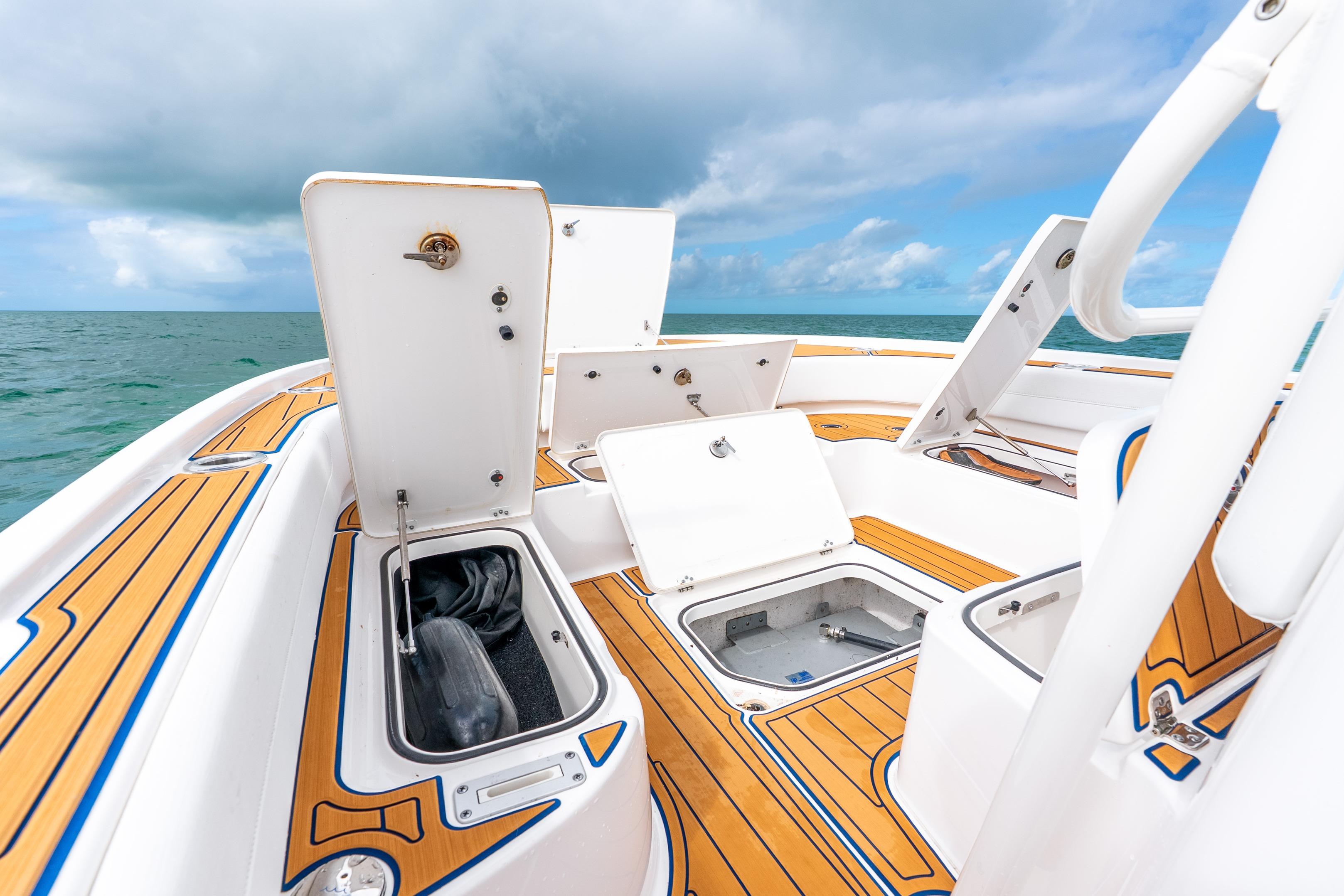 2024 Caymas 281 HB boat deck with open storage compartments, ocean backdrop.