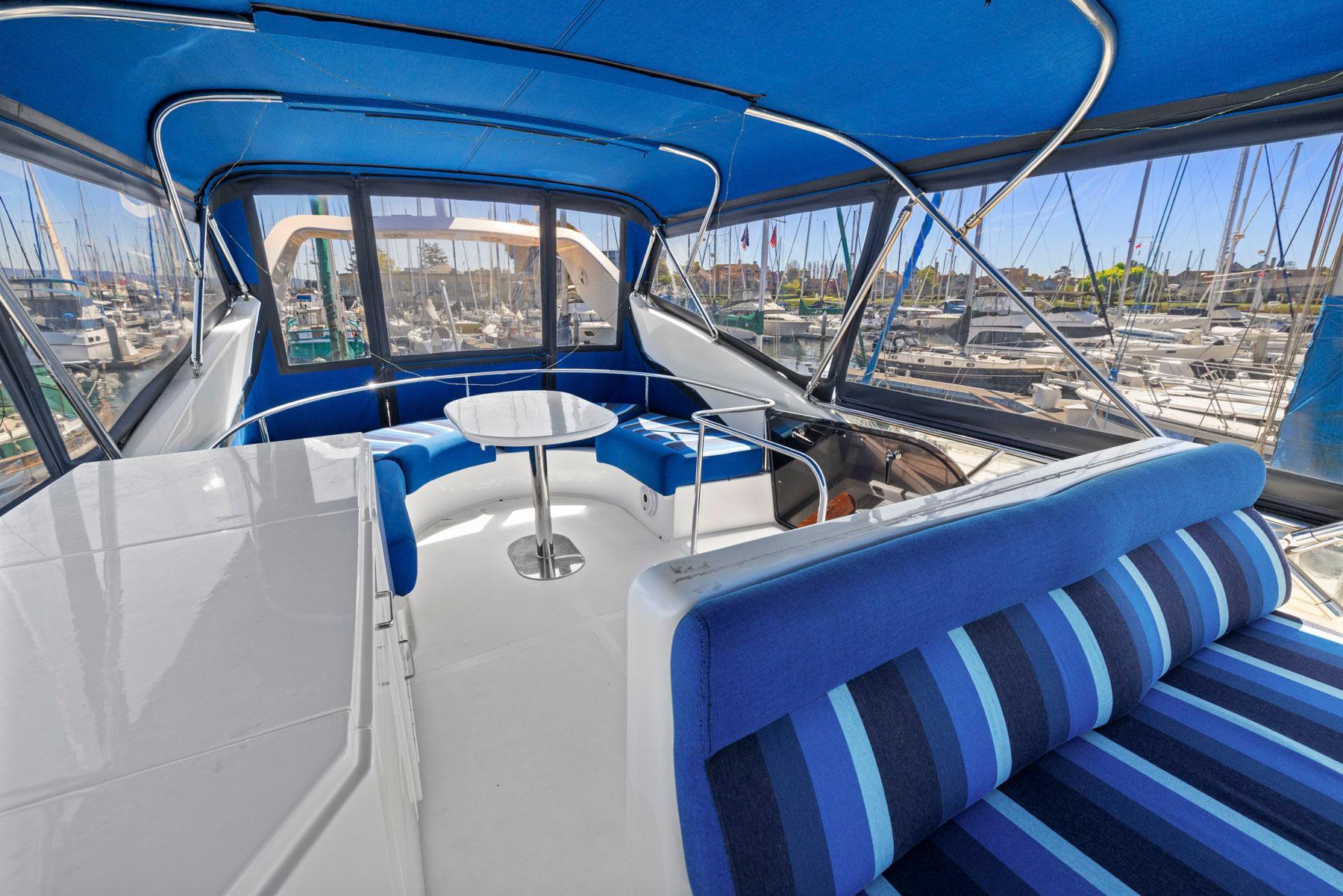 Luxurious 2008 Dyna 51 yacht interior with blue seating and table, docked at marina.
