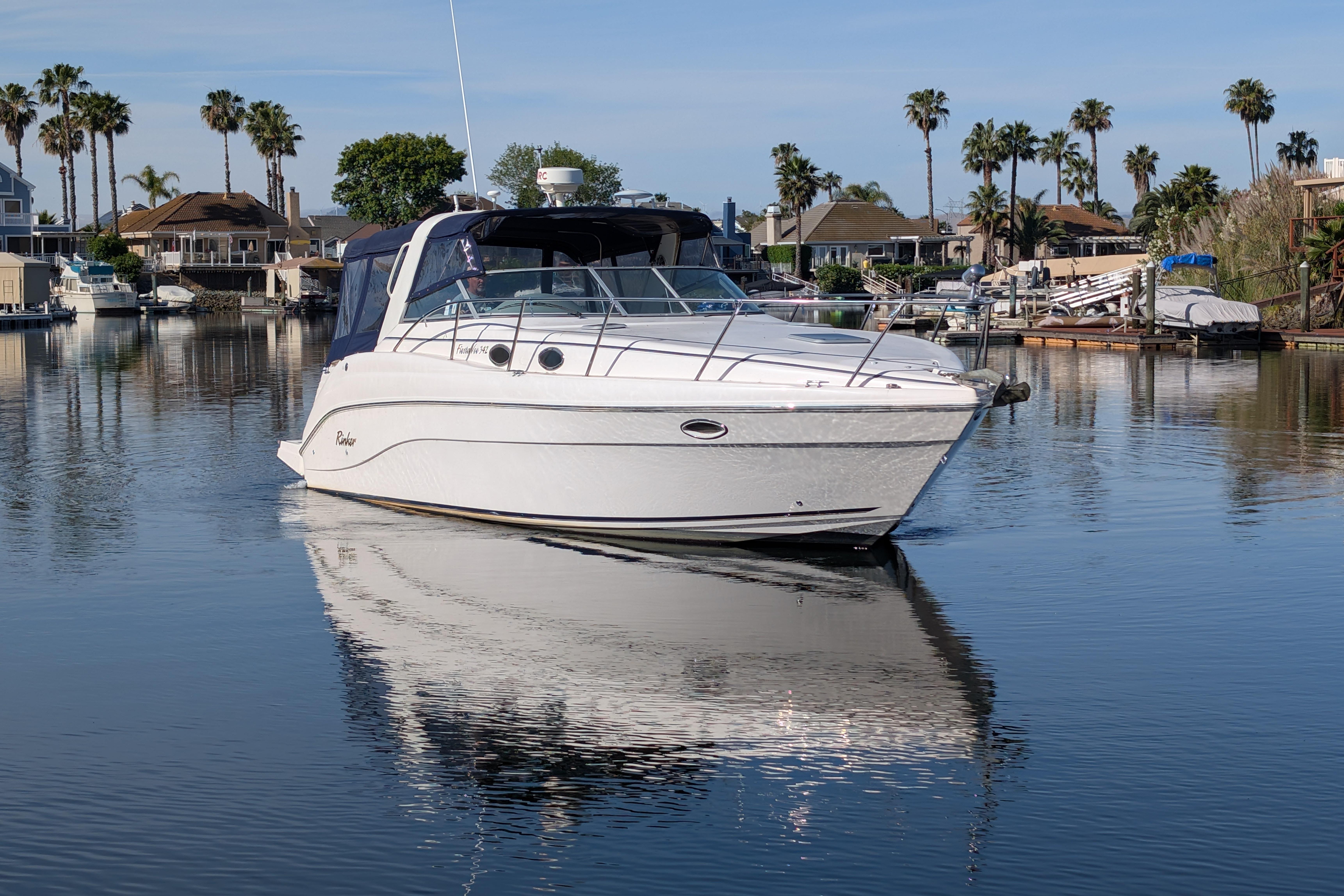 2003 Rinker Fiesta Vee 342 boat on calm water with palm trees in the background.