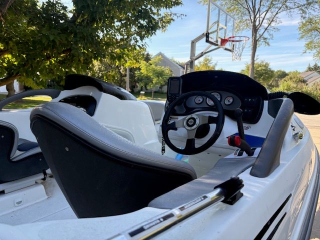 2004 Bombardier Challenger boat interior with steering wheel and controls, parked outdoors.