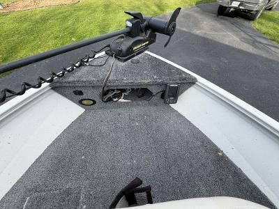 A boat with gray carpeting and a trolling motor on a trailer.