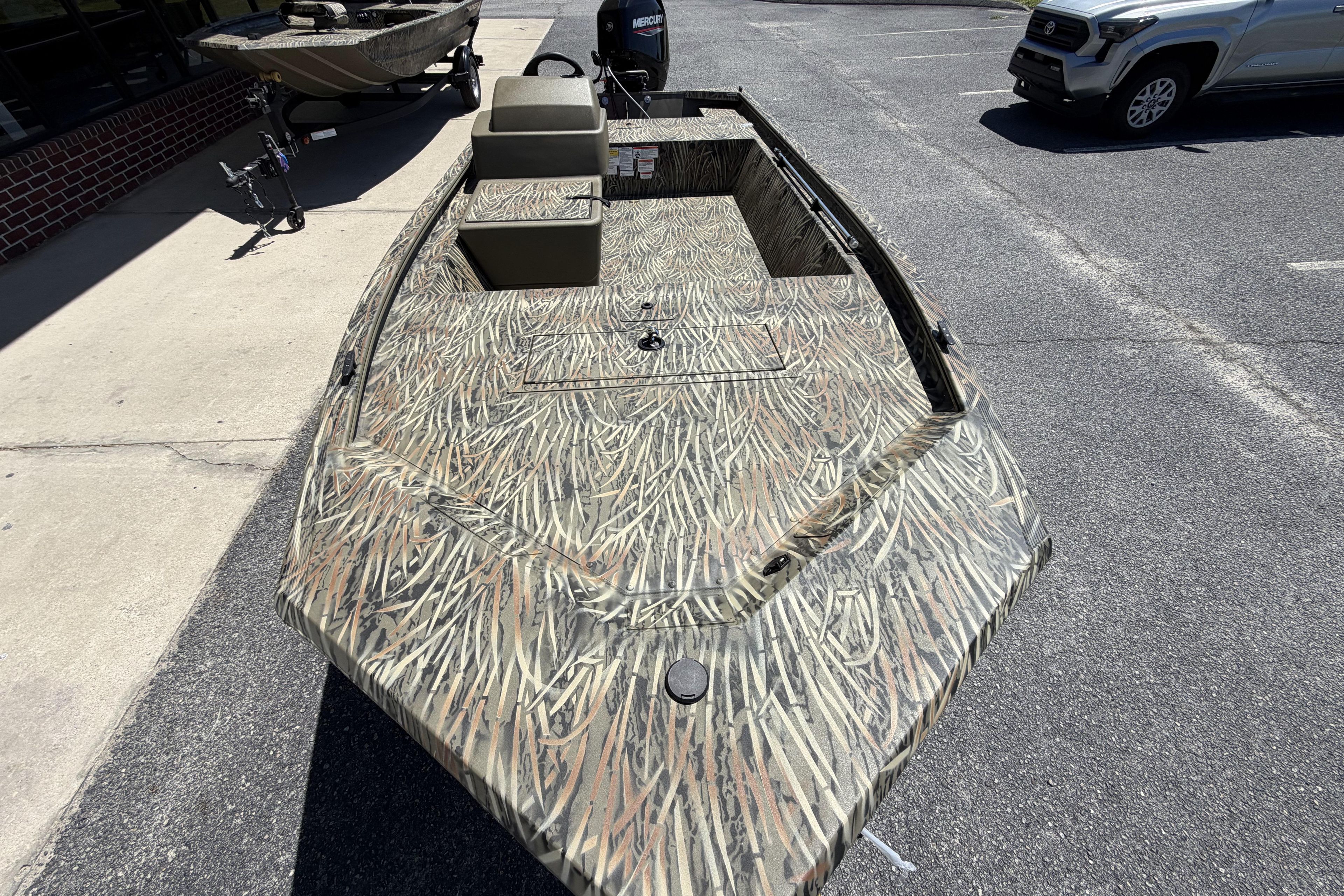 2026 Tracker Grizzly 1648 SC boat with camouflage design parked outdoors.