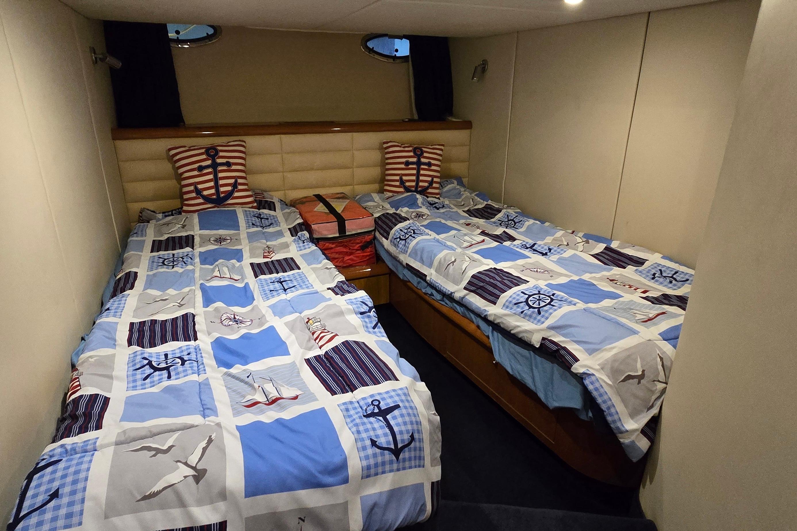 Twin cabin with nautical-themed bedding in 2004 Sunseeker Camargue 50 yacht.
