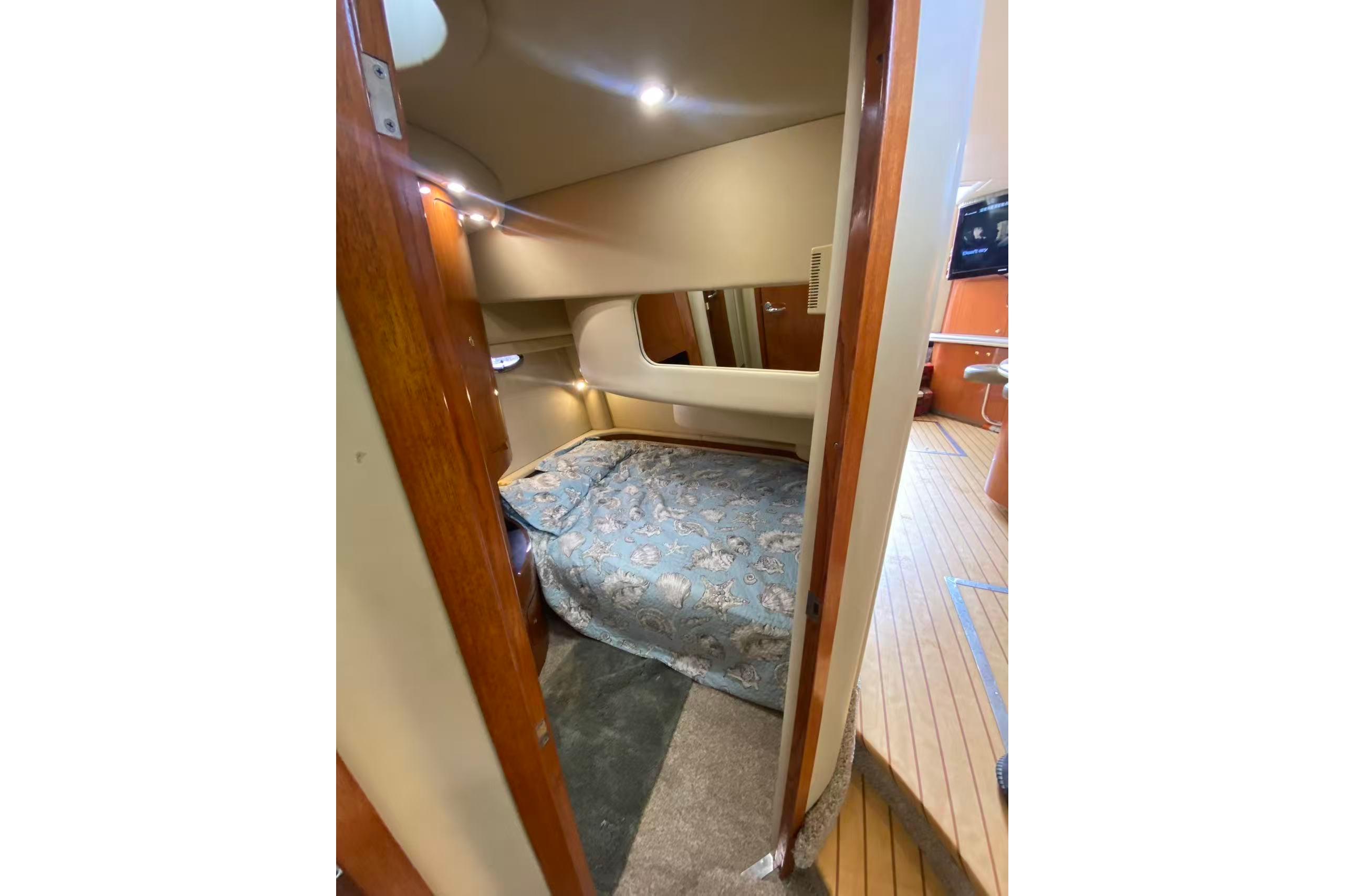 Interior cabin of 2000 Sea Ray 450 Express Bridge with cozy bed and wooden accents.