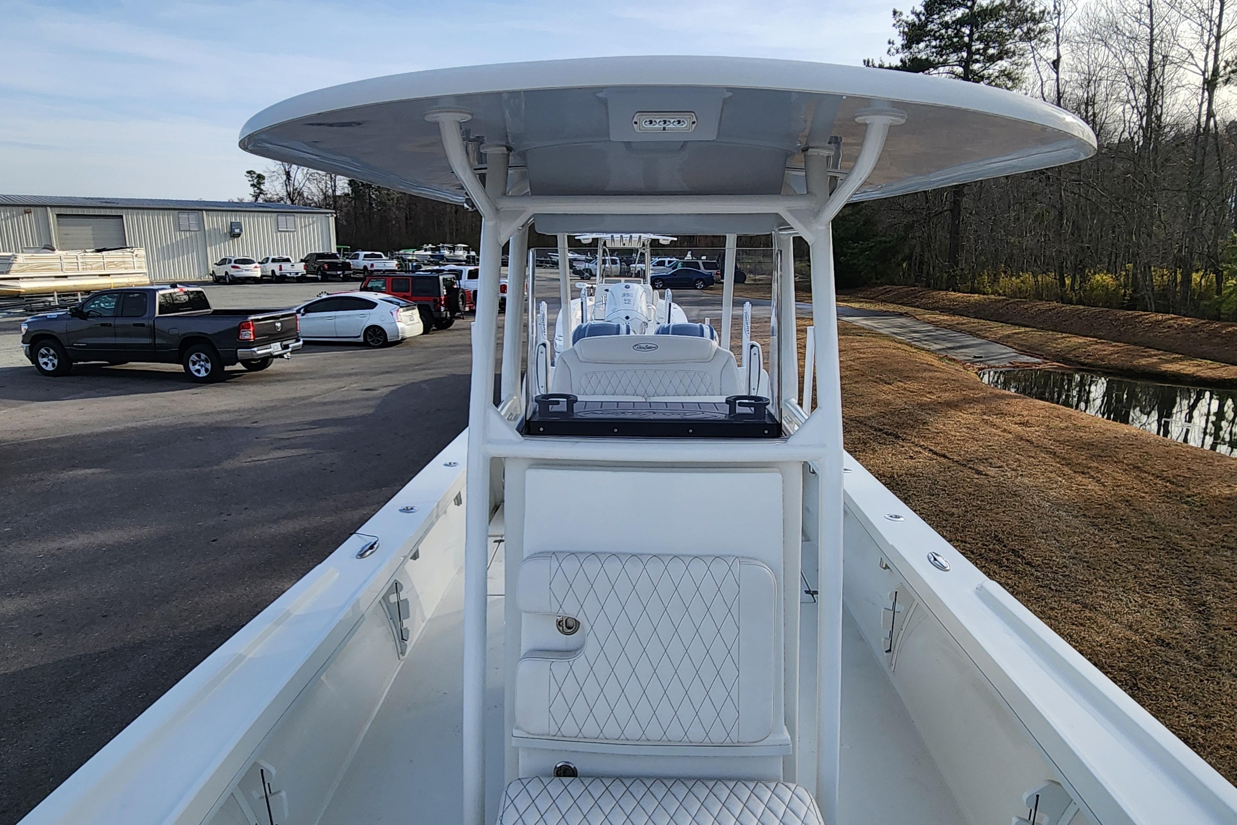 2024 Pair Customs 27 CC boat with sleek design, parked outdoors near vehicles and trees.