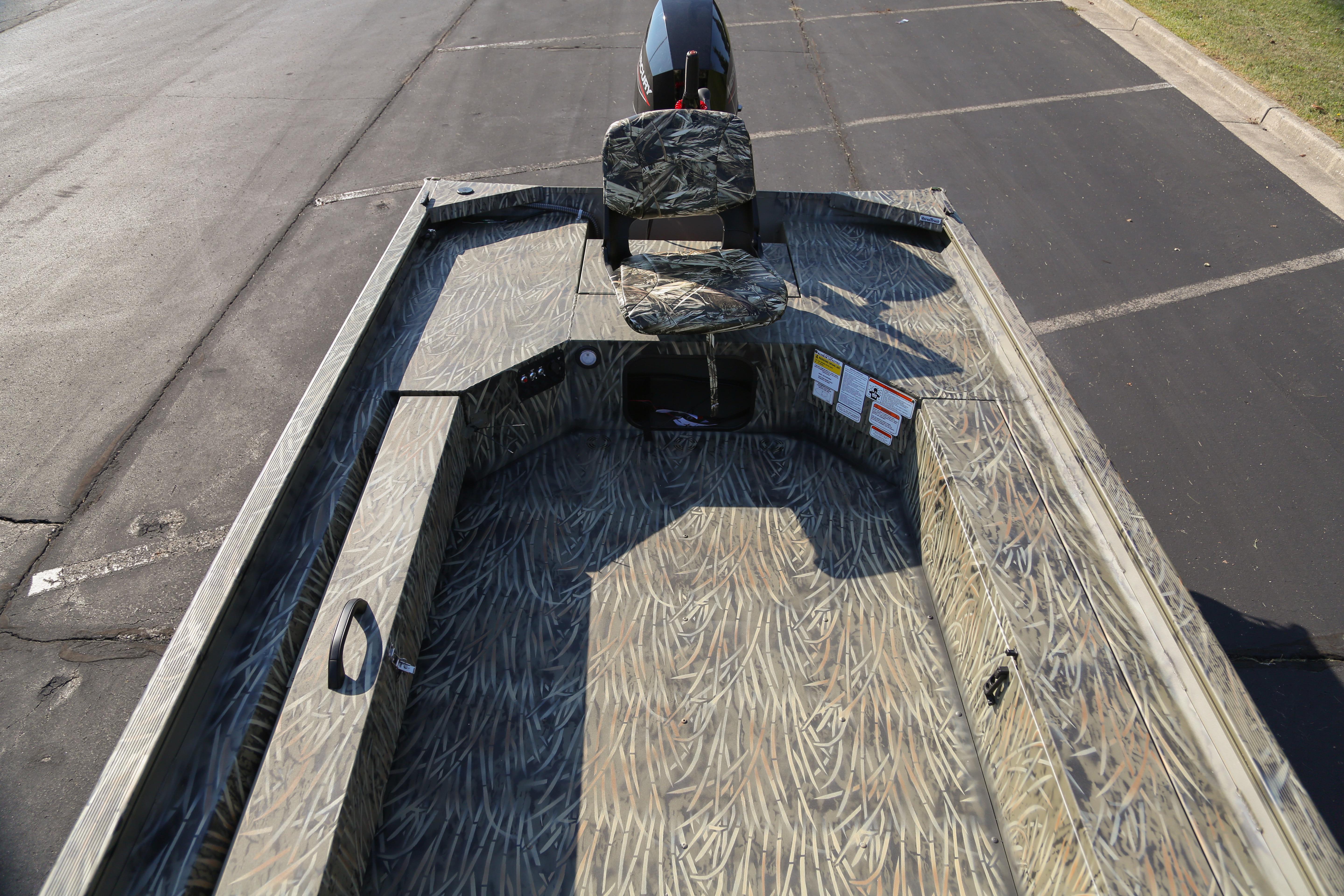 2026 Tracker Grizzly 1654 T Sportsman boat with camouflage interior on a paved surface.