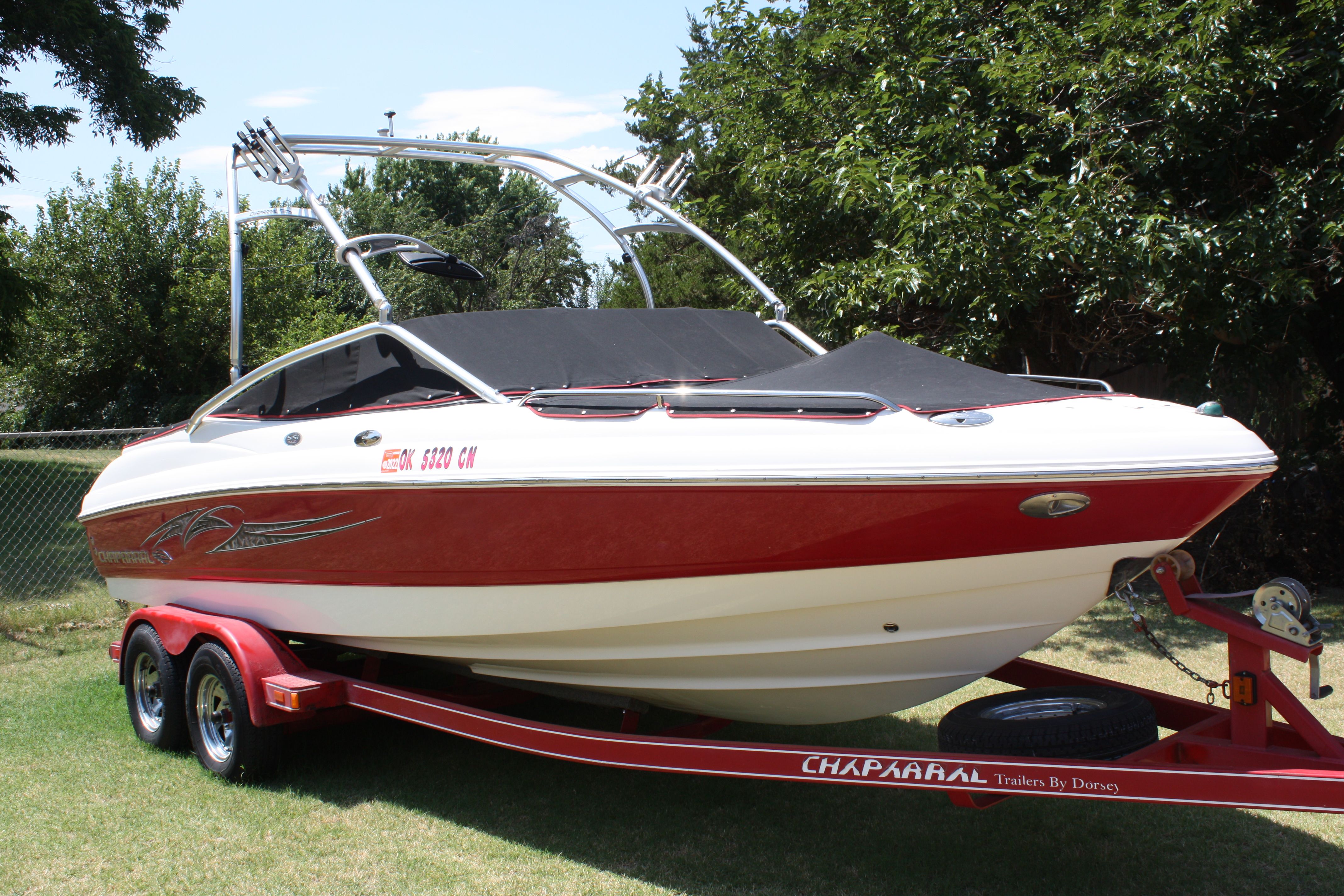 A red 2007 Chaparral 210 SSi boat on a trailer outdoors.