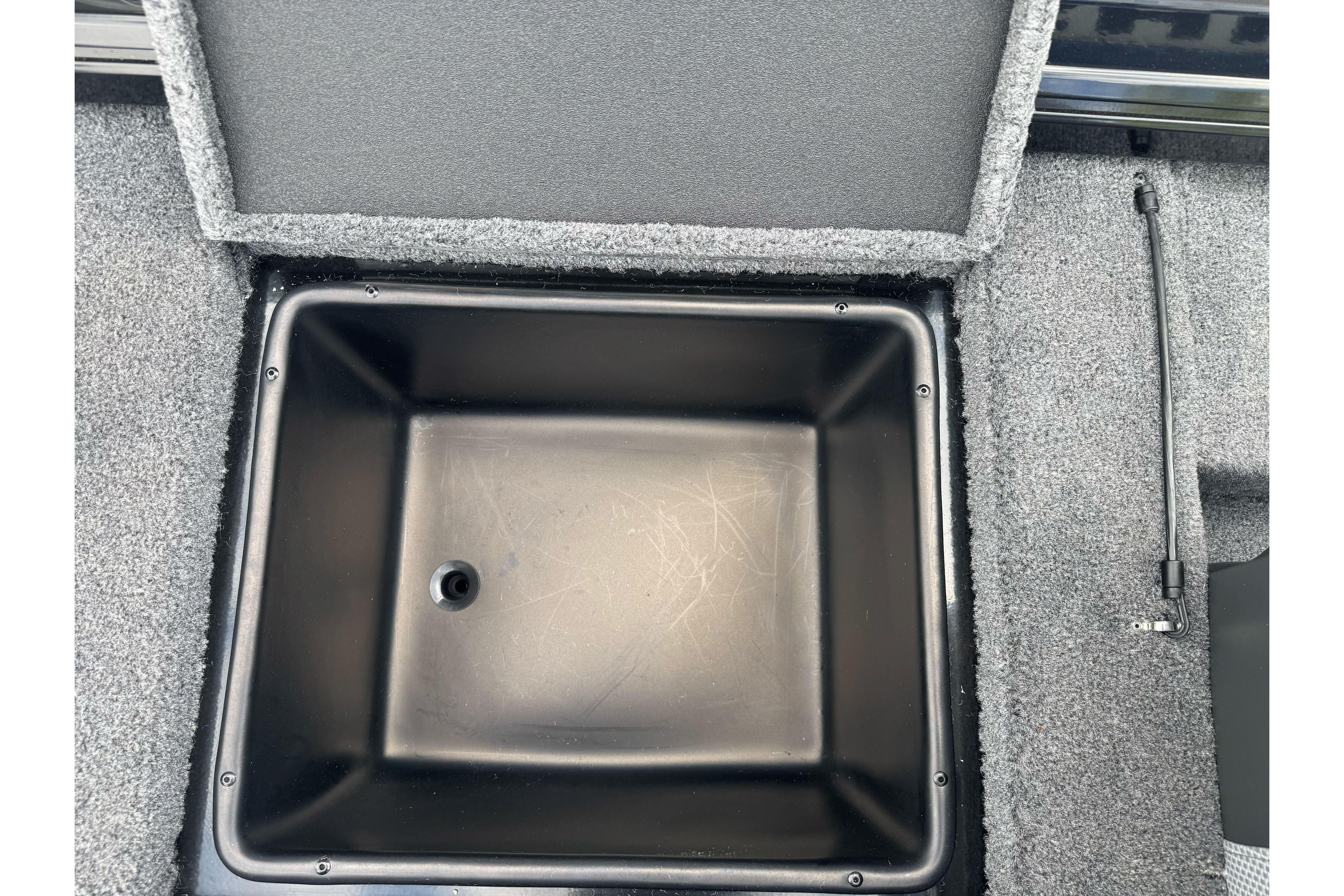 Storage compartment in 2026 Ranger ALPHA 208 boat, featuring a black interior and gray carpet.