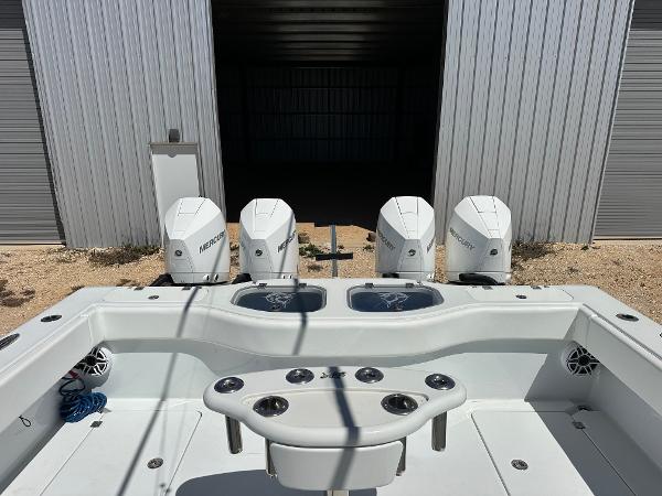 Freeman 42LR 2022 boat with four Mercury engines, docked near a metal building.