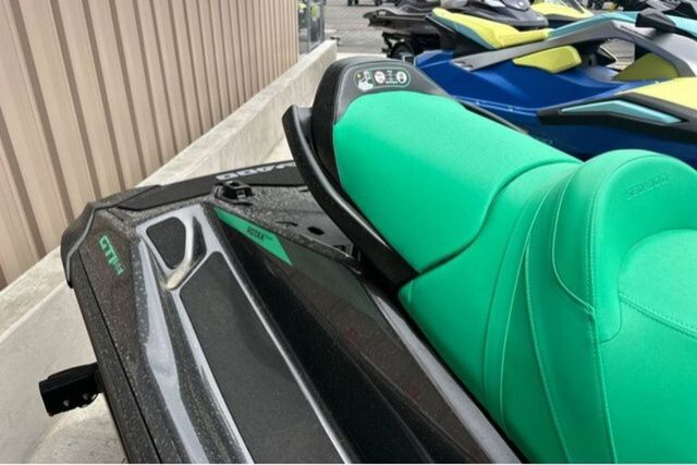 Sea-Doo PWC GTR 230 with green seat and black hull, parked next to other watercraft.