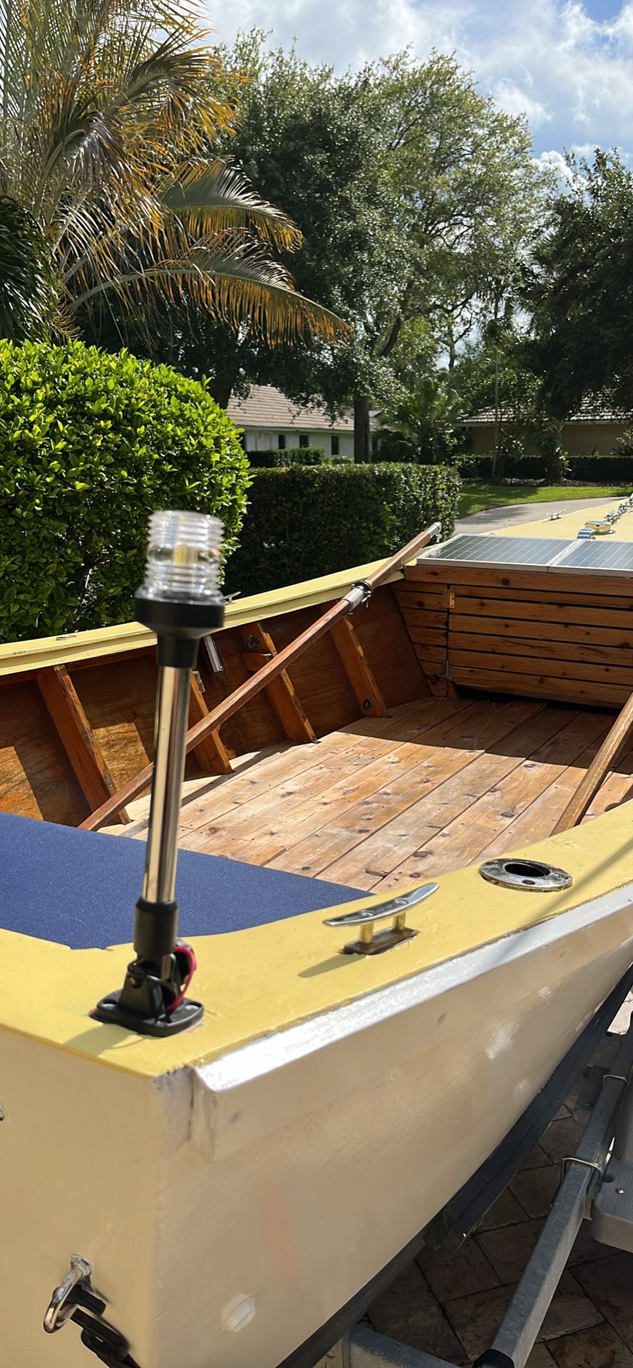 A 2021 Custom Dory boat with a wooden interior and oars, surrounded by trees.