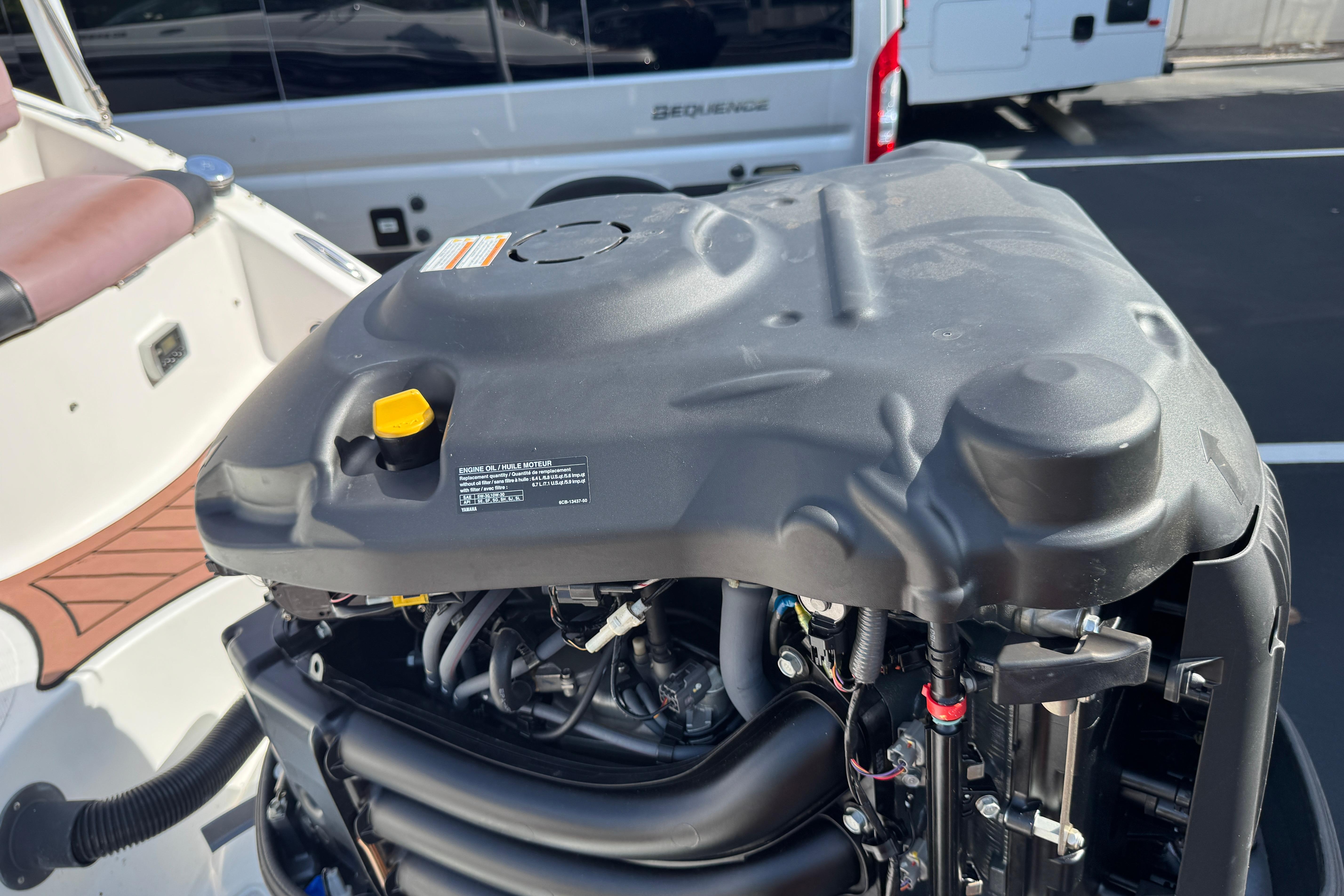 2018 Hurricane SunDeck 2400 OB boat engine close-up in a parking lot.