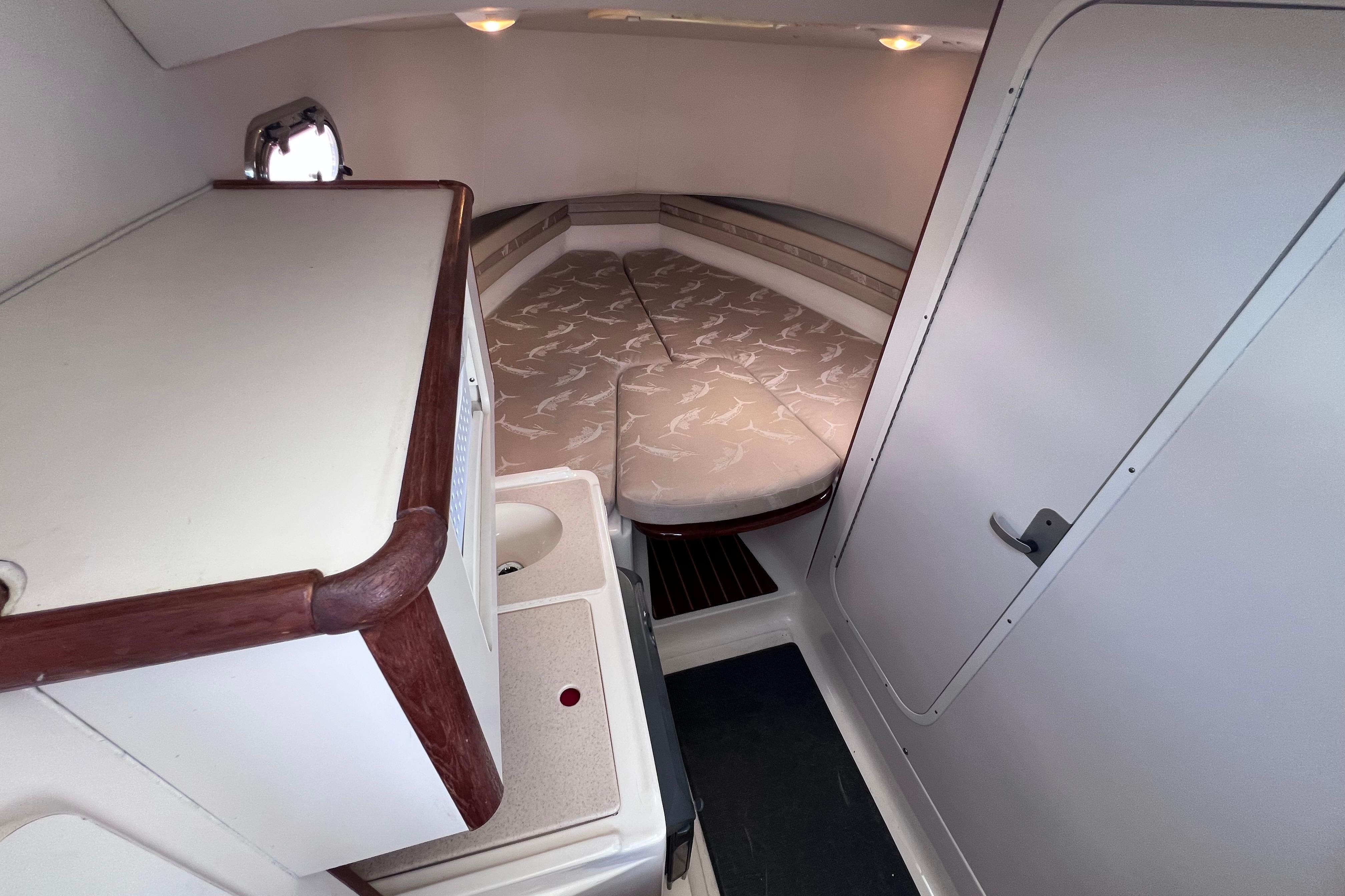 2004 Pursuit 2870 Walkaround cabin interior with bed and compact sink area.