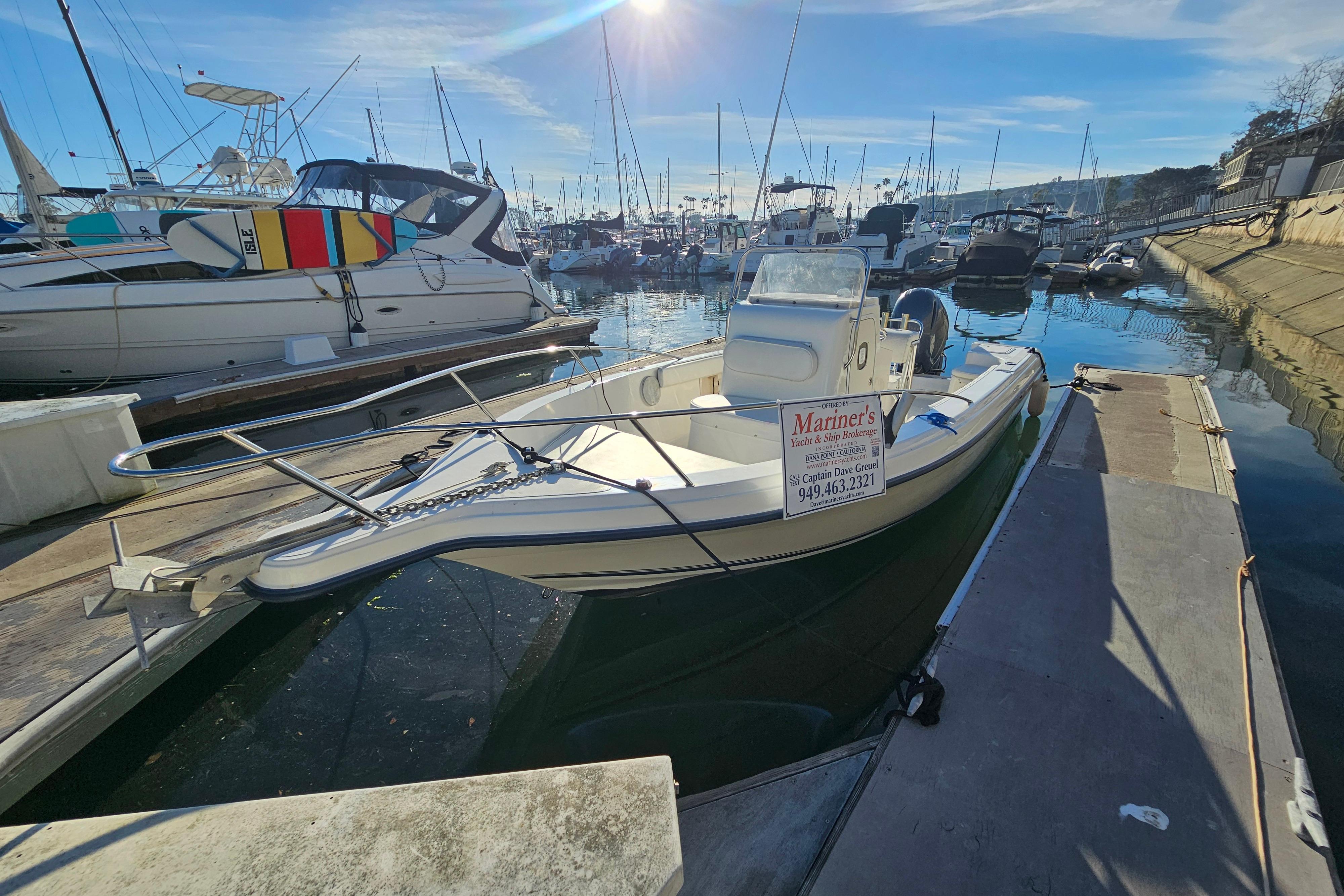 2002 Sea Fox 210 Center Console boat docked in a marina under clear skies.