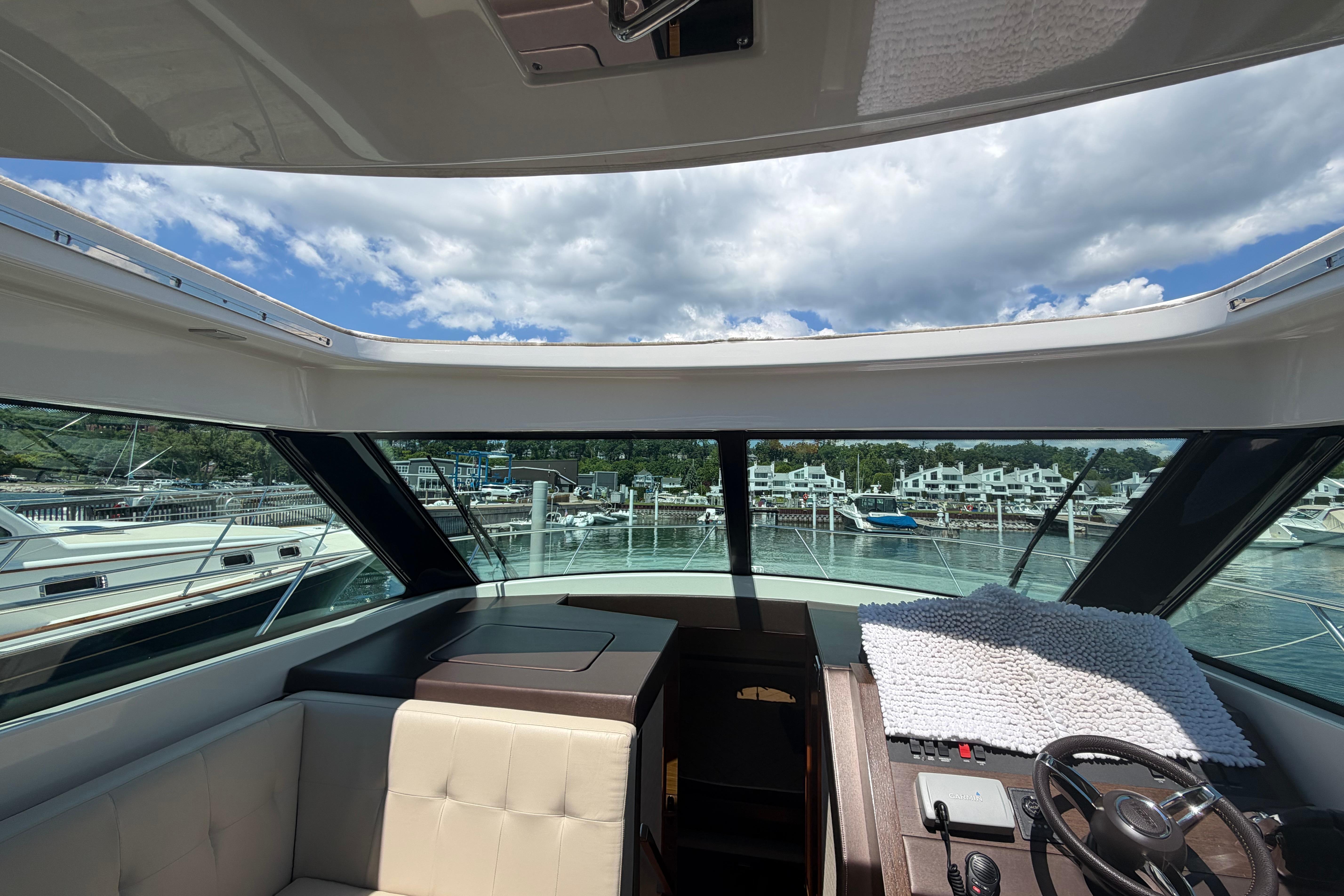 Interior view of 2016 Tiara Yachts C39 Coupe, showcasing helm and marina backdrop.