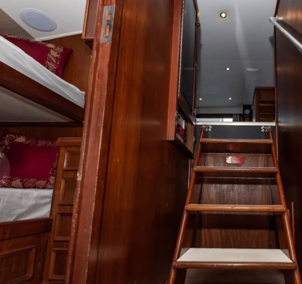 Interior of a 1979 Hatteras sport fishing yacht with wooden stairs and bunk beds.
